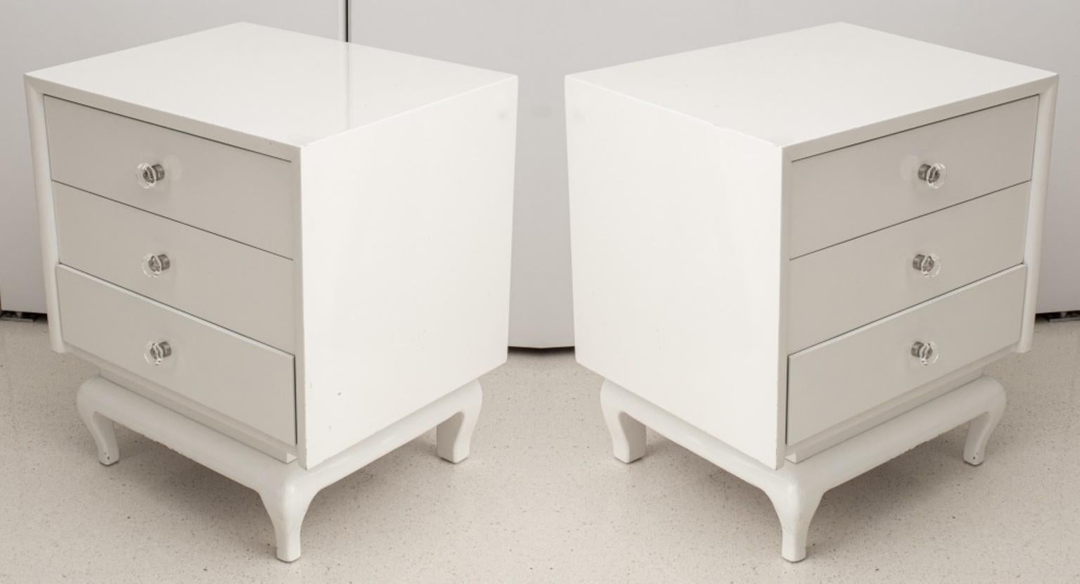 Pair of Modern white lacquered wood nightstands with three drawers above four cabriole feet, with octagonal glass pulls, in the manner of James Mont. Each: 24.5