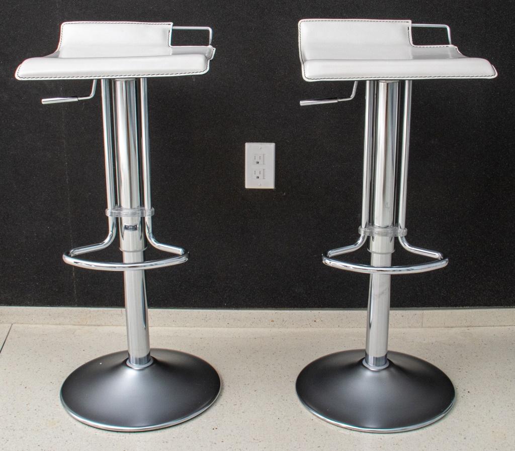 Pair of adjustable chrome bar stools raised on circular pedestal, white faux leather seat. Each: 32.5