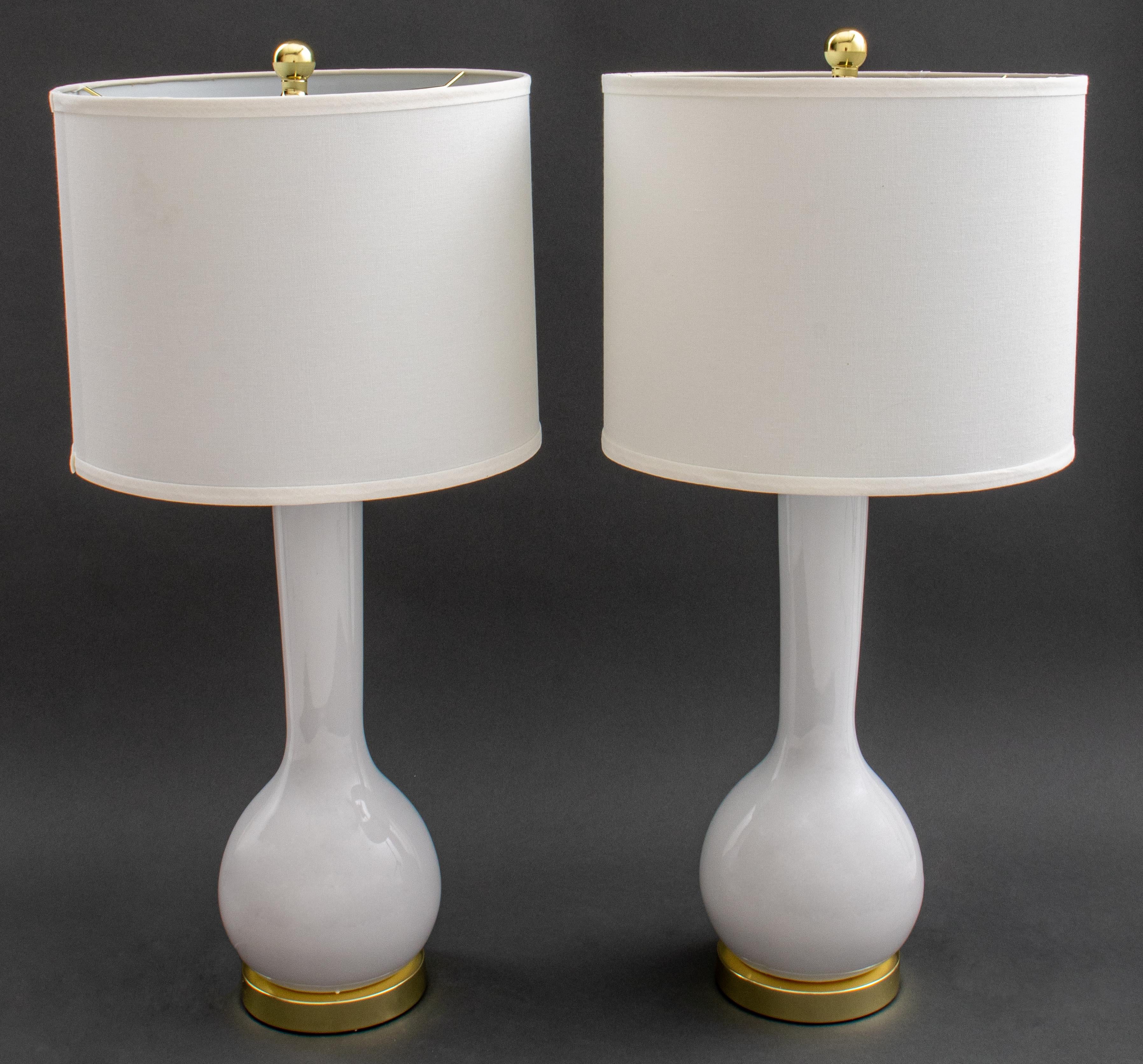 Pair of modern white porcelain bottle vase form lamps with gold-tone metal harps, circular bases, and finials, marked to undersides. 30.5