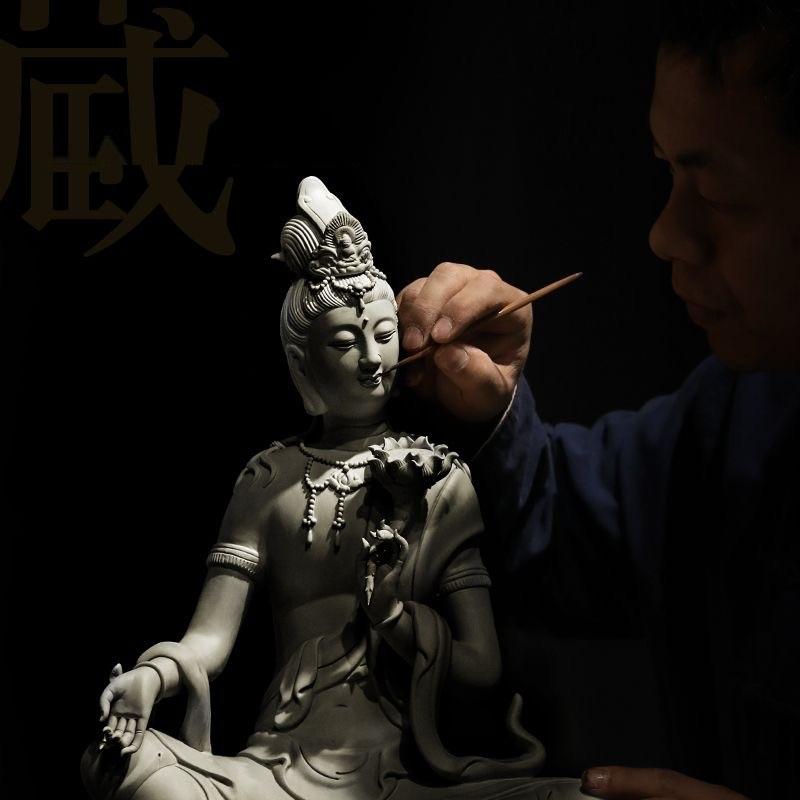 The white porcelain statue of a sitting Buddha dressed in a blue robe and holding a lotus flower is a striking piece that combines artistry with profound spiritual symbolism.

White porcelain, particularly from renowned Chinese kilns such as those