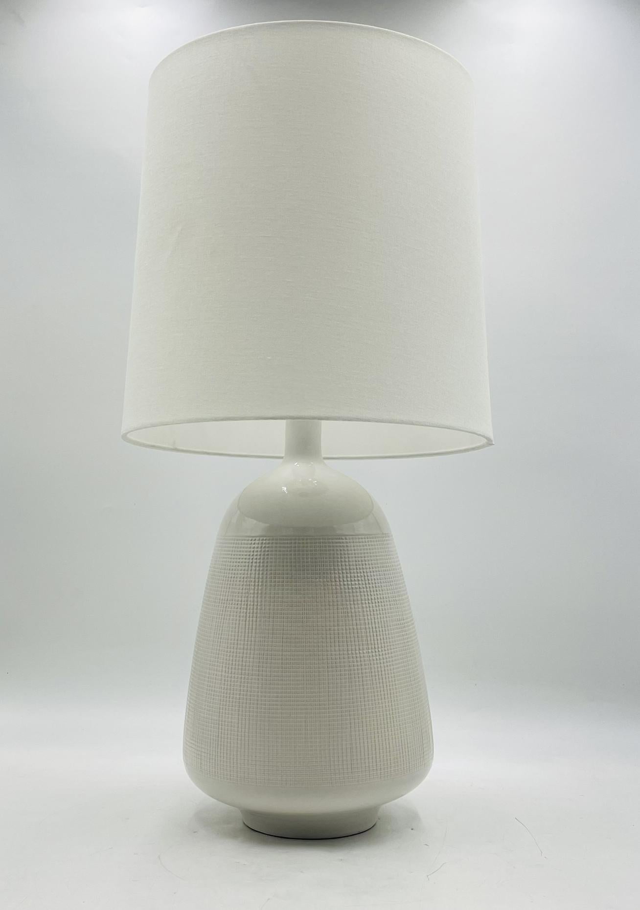 Sofisticada y versátil, la lámpara de mesa Ornella de Aerin para Visual Comfort Studio combina una refinada artesanía con una silueta atemporal. La base de cerámica suavemente ahusada muestra una textura reticulada meticulosamente aplicada bajo un