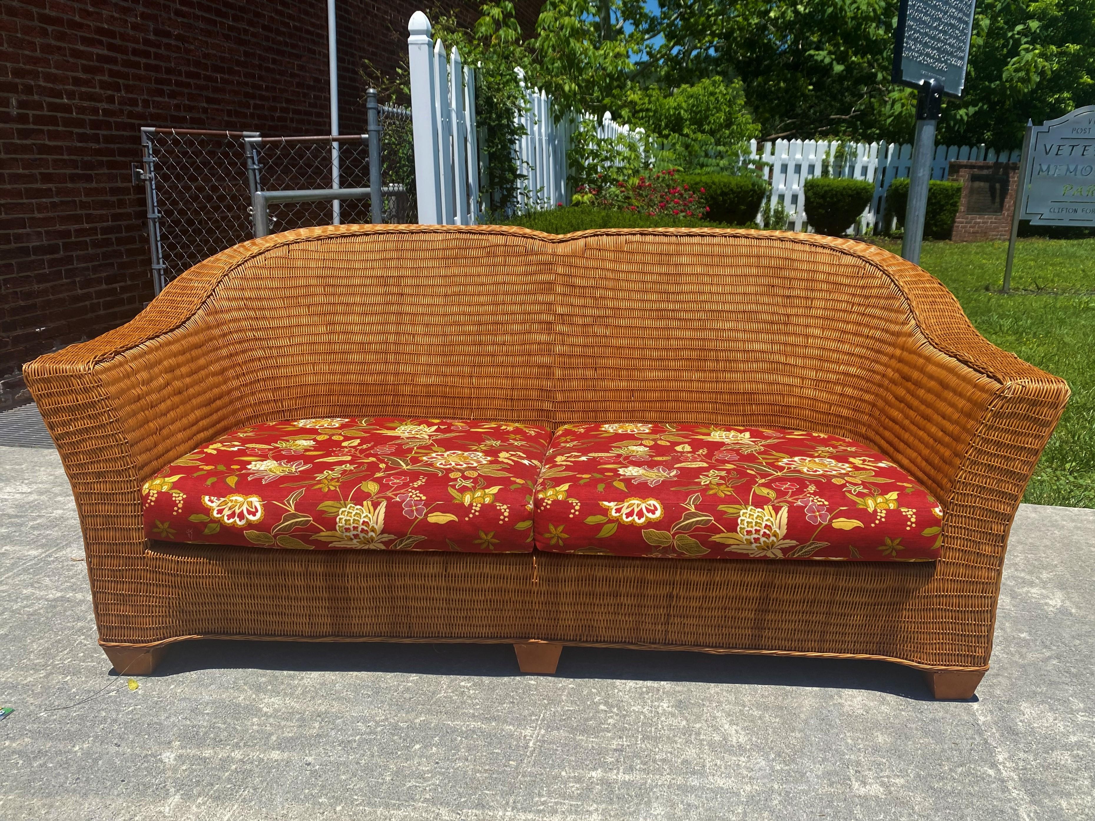 This is a wonderful modern style double hump back wicker sofa with beautiful brown & cranberry variegated background & floral upholstery which has a tag from M.C, Interiors & Fabrics, Gaithersburg, MD and a tag on the bottom of the sofa dating it