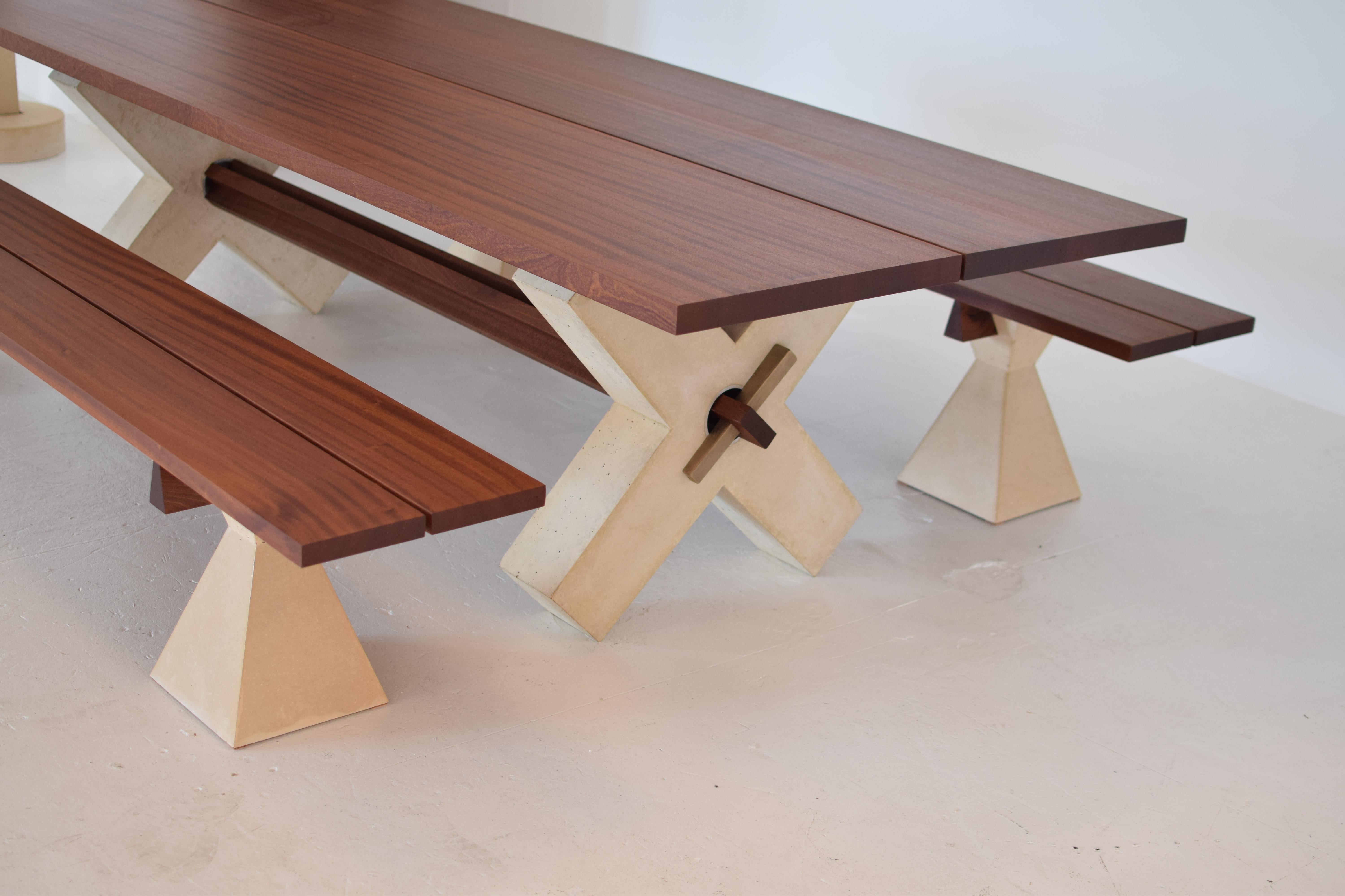 X dining table
This substantial wooden top and monument X-base make for a grand dining experience. Poux’s use of cast concrete commands attention, this time with the addition of his two-piece tabletop and wood trestle beam that connects the