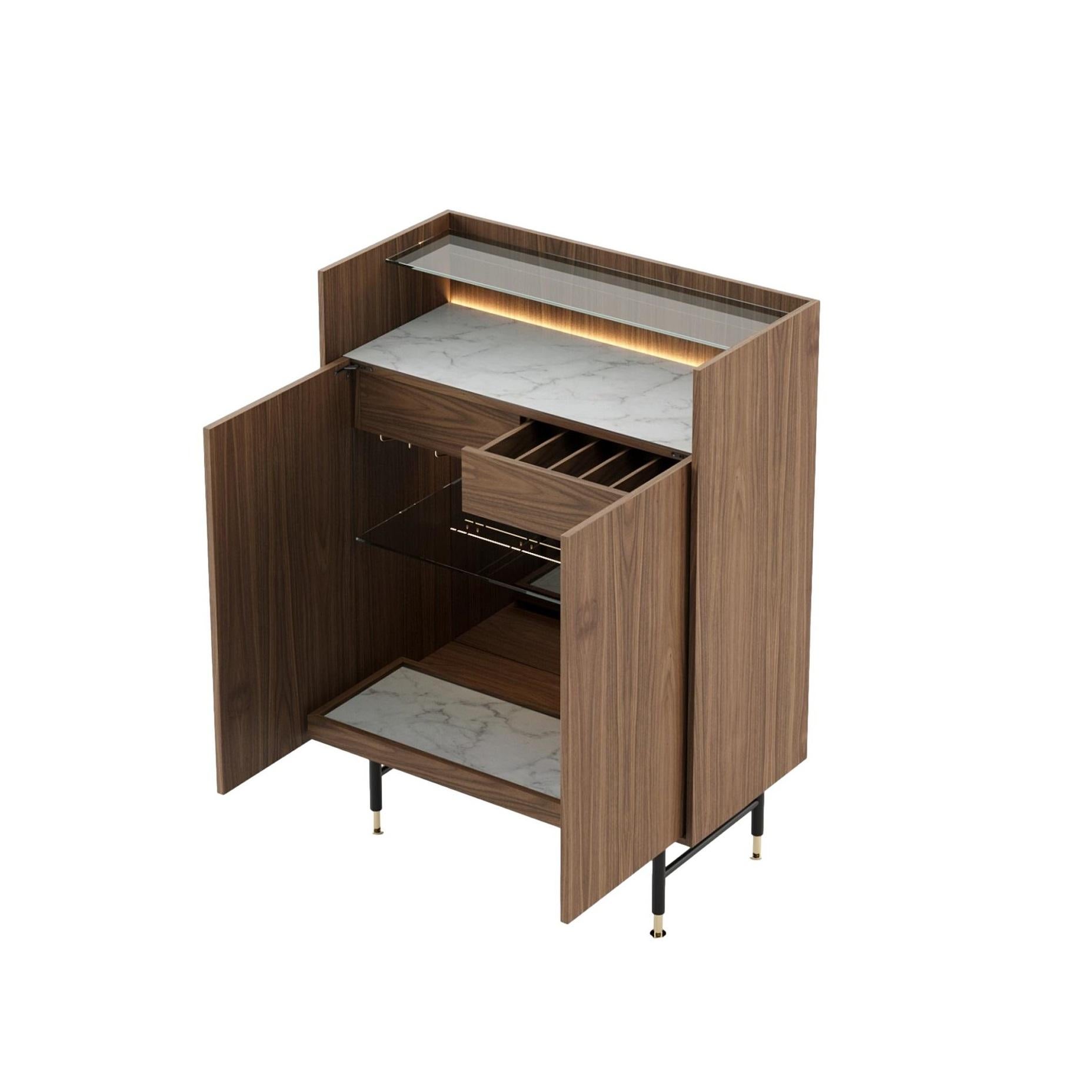 È un mobile bar moderno che ridefinisce la semplicità. Il suo design elegante è caratterizzato da una sapiente combinazione di vetro trasparente e sottili accenti di marmo, che creano un'atmosfera aperta e ariosa. Perfetto per chi apprezza