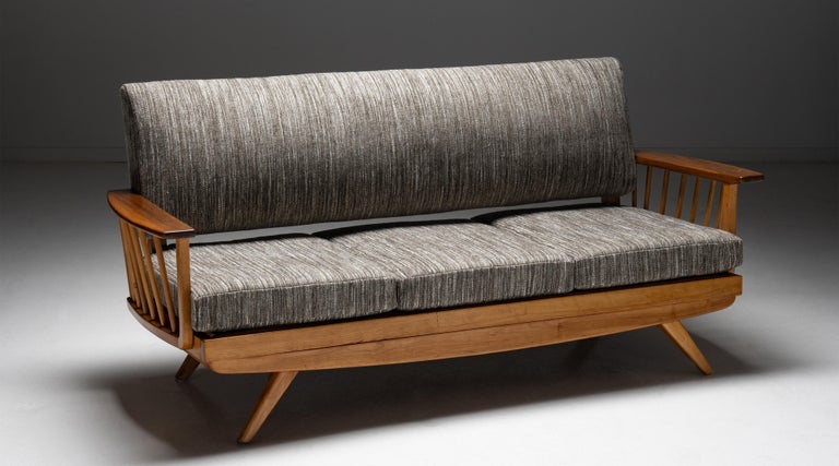 Modern wooden sofa, England circa 1960.

Upholstered seat and back with solid wood platform base and armrests. On splayed wooden legs. In the style of Nakashima.