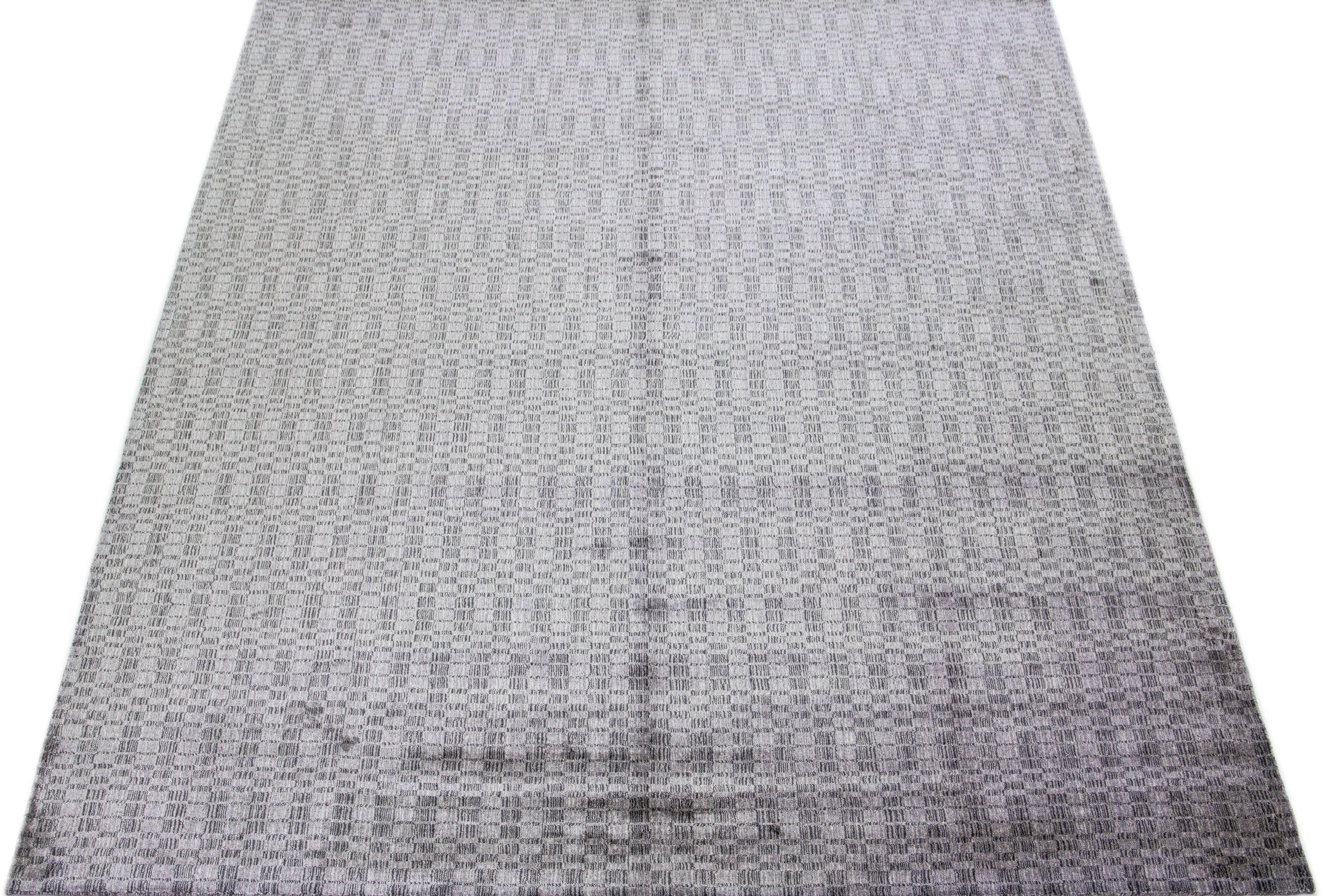 Cet exquis tapis contemporain en laine et soie présente une base gris-argent frappante ornée d'un étonnant motif géométrique qui s'étend gracieusement d'un bout à l'autre.

Ce tapis mesure 9'11