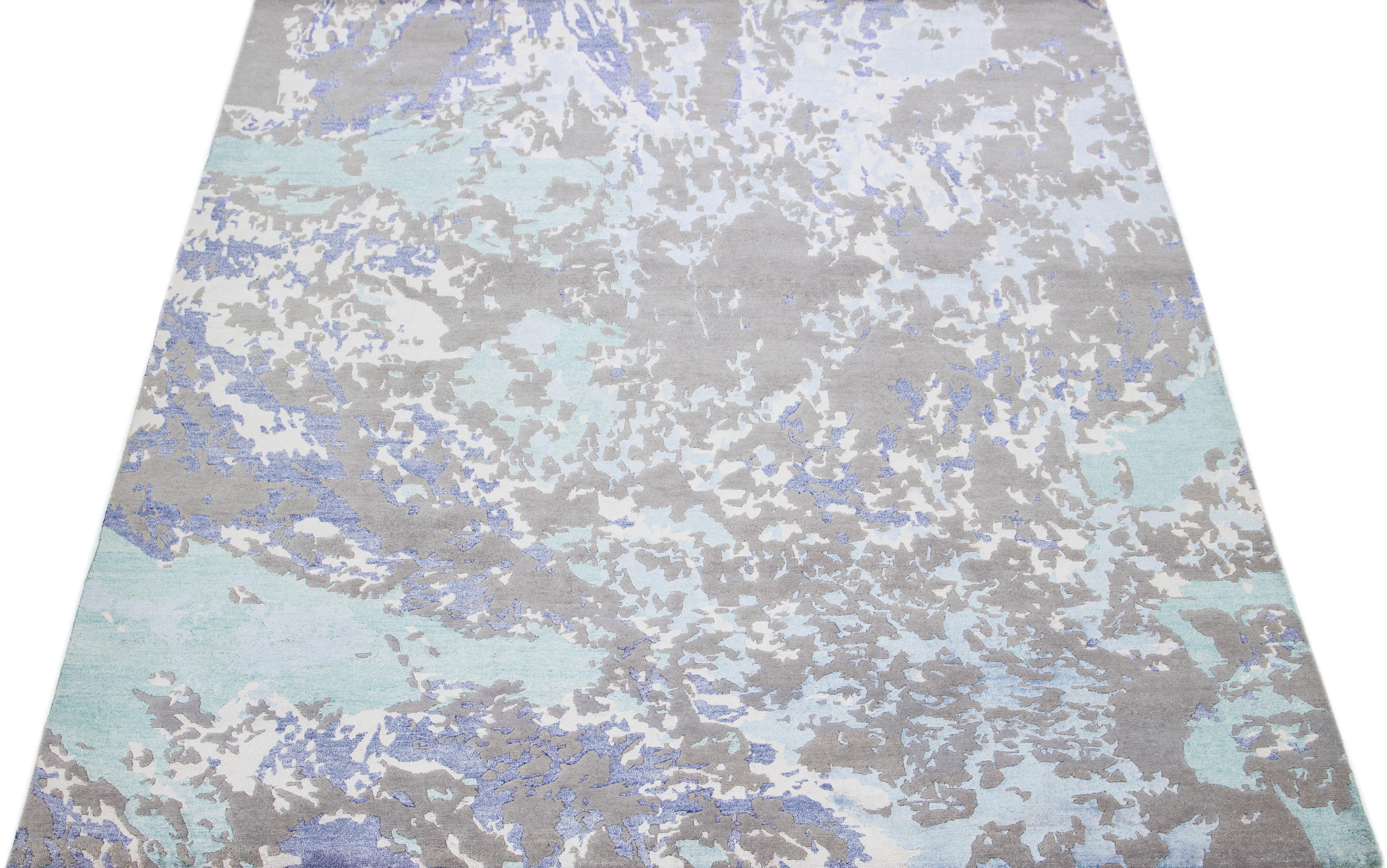 Preciosa alfombra moderna india de lana y seda con un campo azul claro en un dibujo abstracto de color verde azulado, gris y marfil. Las fibras de lana y seda proporcionan un tacto lujosamente suave, mientras que su baja altura de pelo aumenta la