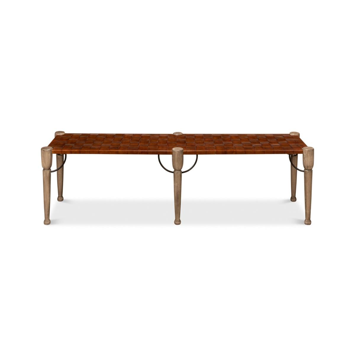 Modern woven bench with a brown woven leather seat raised on turned and tapered naturally finished legs, with iron brackets.

Dimensions: 68