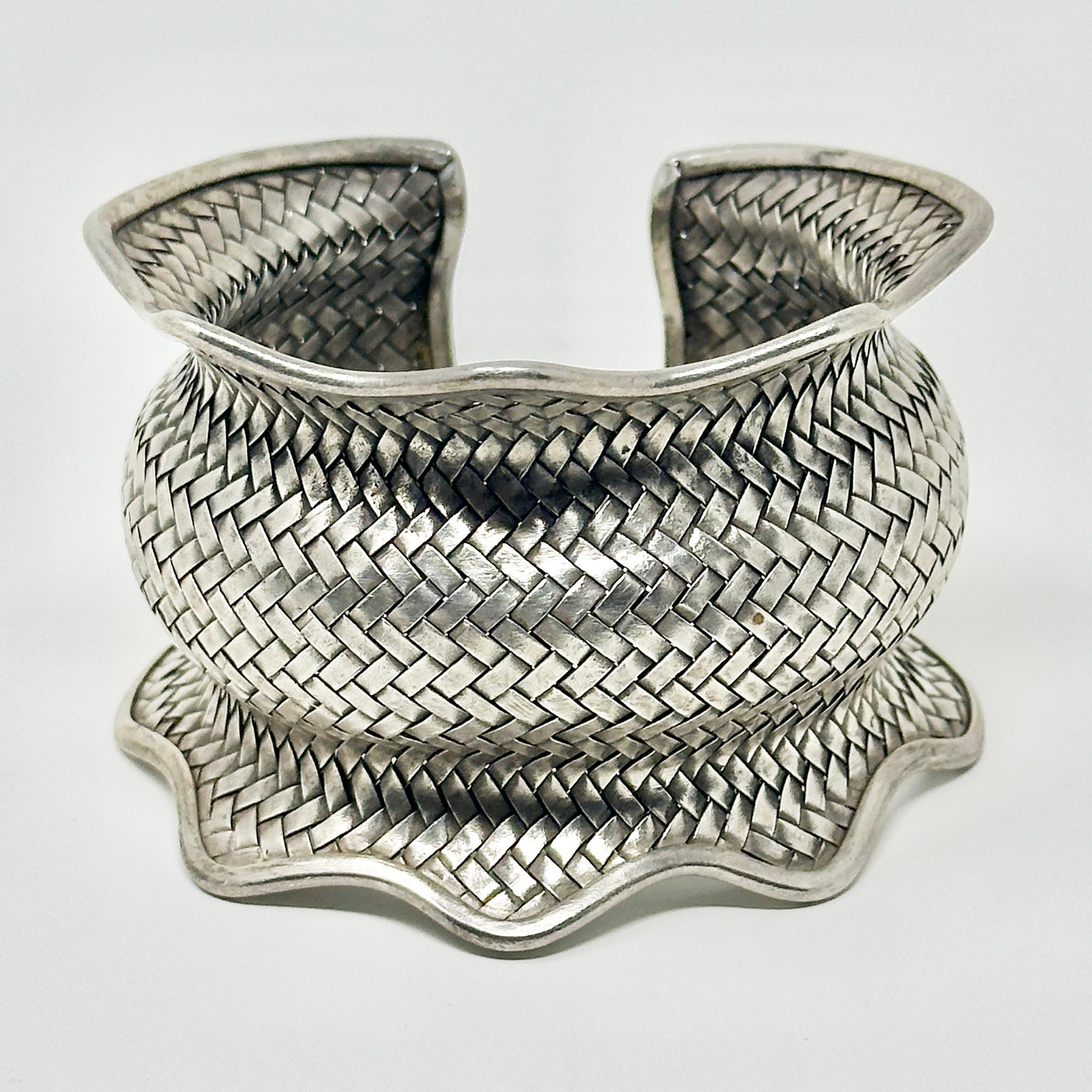 Un bracciale moderno in argento finemente intrecciato con bordo increspato, forse proveniente dalle Tribù delle Colline del Laos. Timbro 925 sul bordo. Misura regolabile, diametro interno di 2,5 pollici e altezza di 2 pollici; peso di 72 grammi. 

