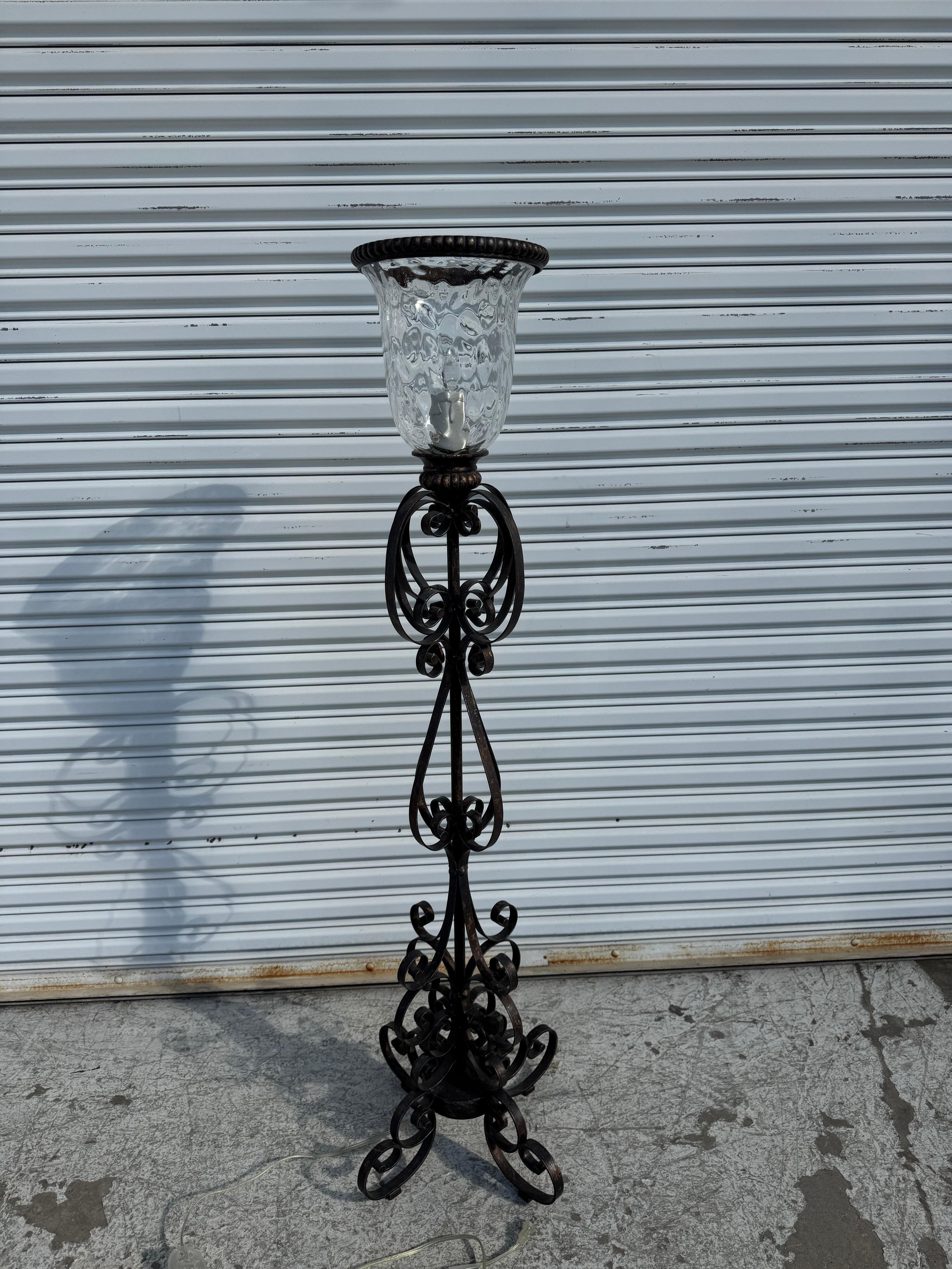 This floor lamp has a handblown glass shade and is crafted from wrought iron..
The wrought iron has a French styled.
It ha some really nice metalwork. 