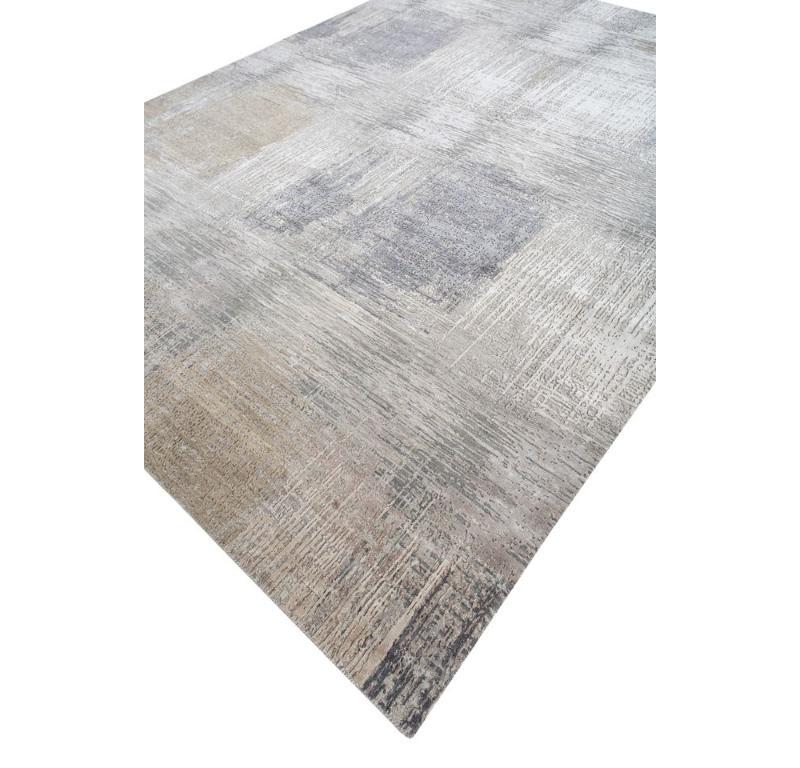 Intrigued by the interplay of textures and serenity? This handknotted masterpiece by boasts a captivating mesh of textures, interwoven with abstract designs that weave a calming atmosphere. The cool, contemporary palette of classic gray, accented by