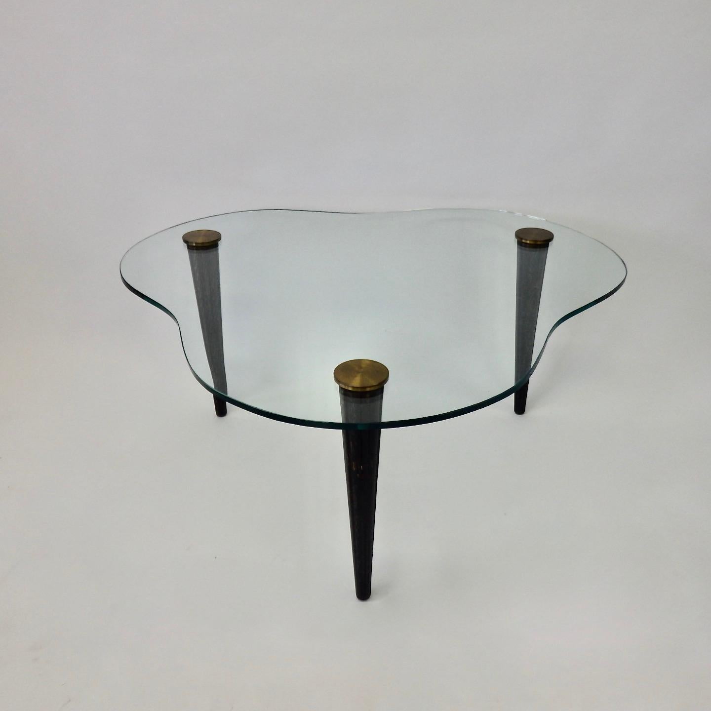 Three fluted ceruse finish legs support biomorphic shape glass top table. By Modernage in the style of Gilbert Rohdes cloud tables.