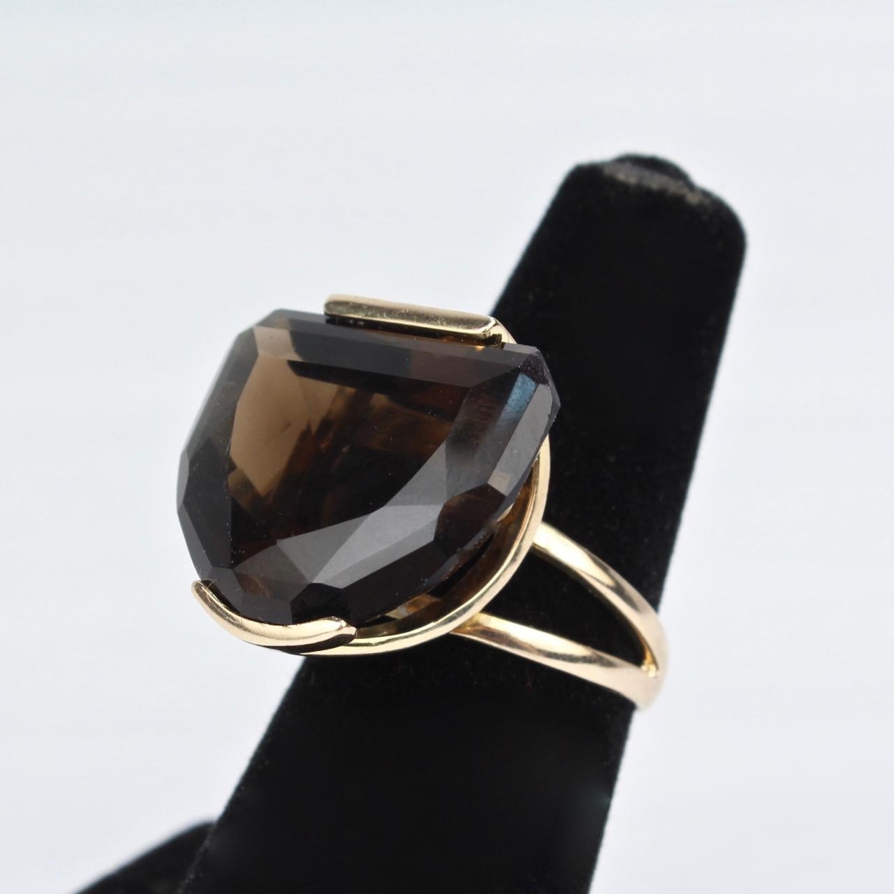 A big Modernist 14K yellow gold cocktail ring.

With a half-moon smoky topaz gemstone tension set in semi-circular open basket. 
It has a split shank that repeats the 'open' design of the basket.

Stamped 14K to the shank for gold fineness.

A great
