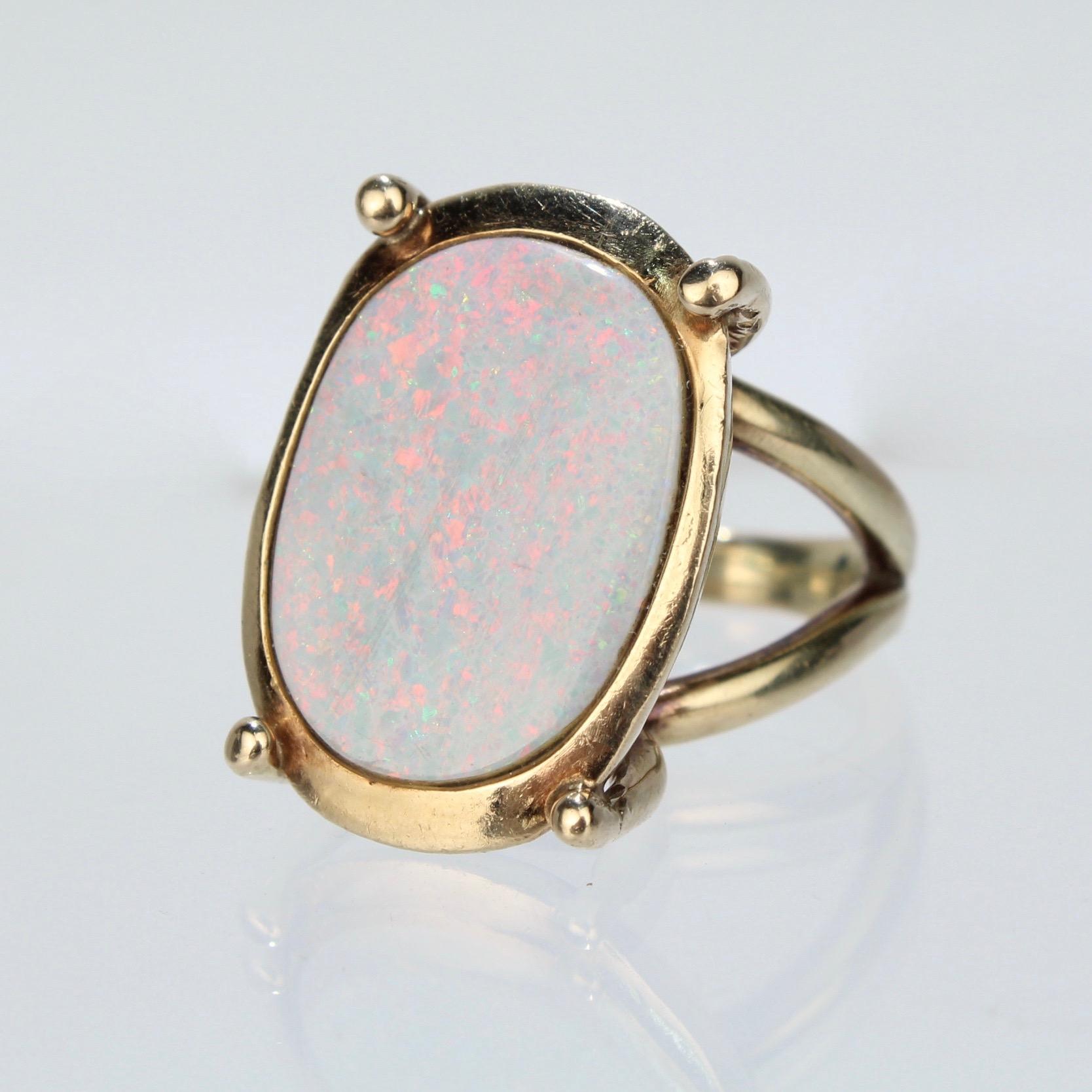 A terrific modernist Opal cocktail ring.

With an oval bezel set opal gemstone mounted in a high-prong setting.

The split shank is asymmetrical and is balanced to show the opal beautifully on the hand.

Unmarked for gold fineness. Professionally