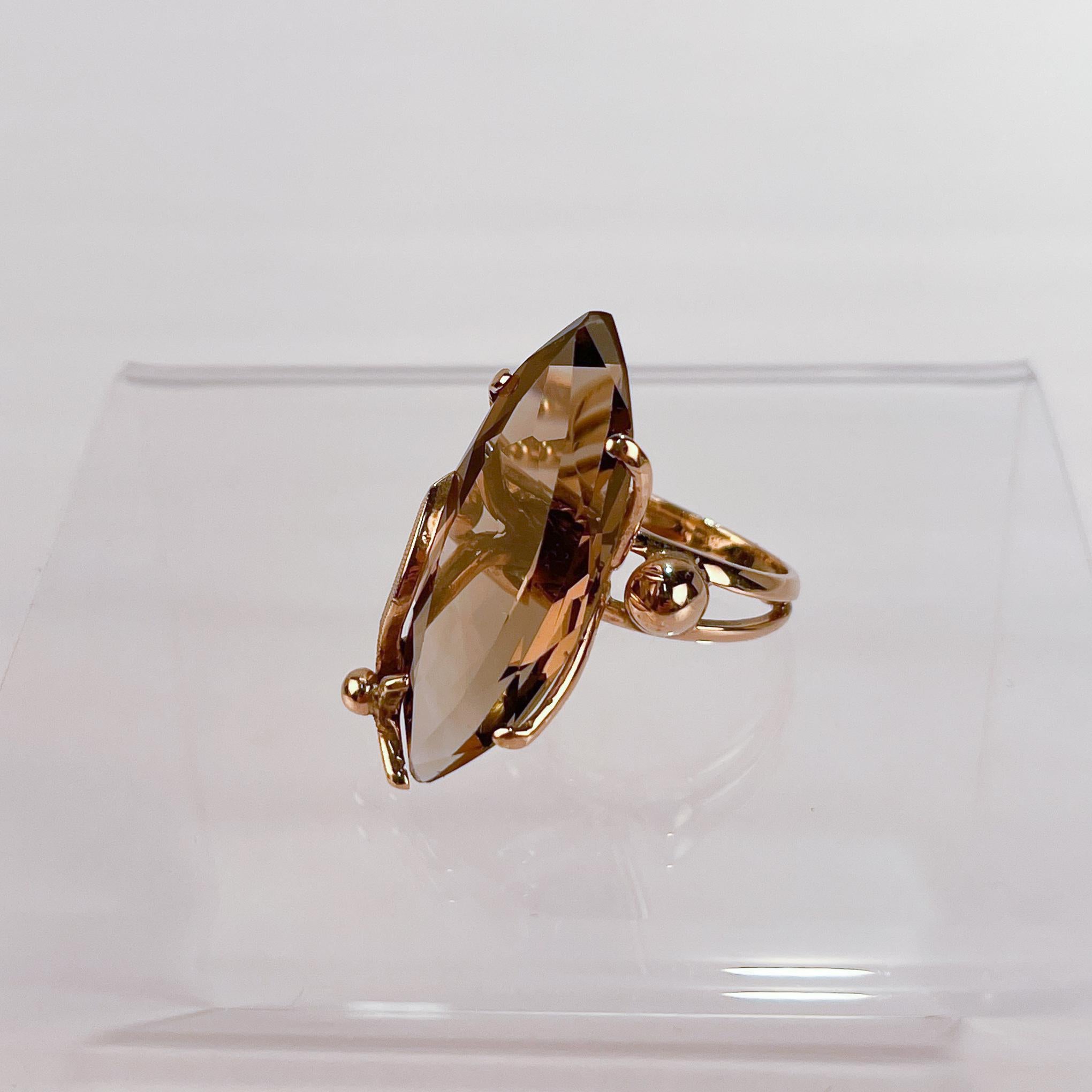 A very fine Modernist 14k gold and smoky quartz cocktail ring.

With a large faceted marquise shaped smoky quartz gemstone prong-set in 14k gold. 

The ring's split shank is made of two wires with two half gold beads that flank the stone.

Simply a