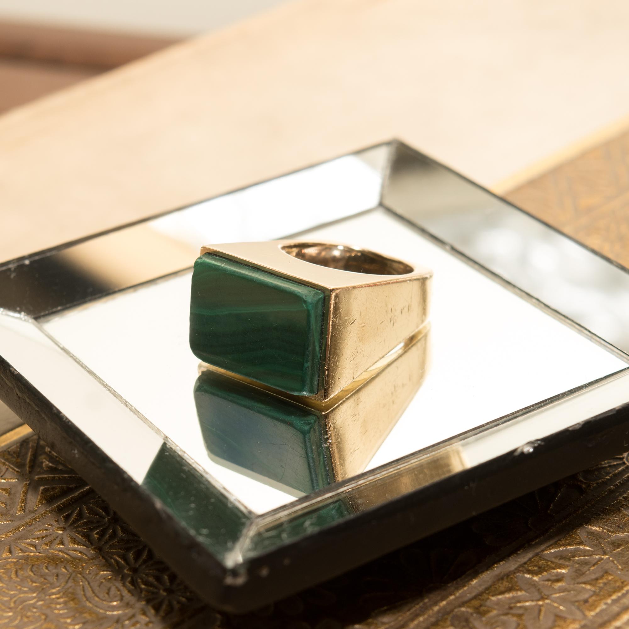 An incredible modernist 14K malachite inlay signet ring. Features a tall geometric design with sleek edges and polished angular sides. The focal point of this piece boasts a flat rectangular slab of malachite, slightly raised in a horizontal bezel