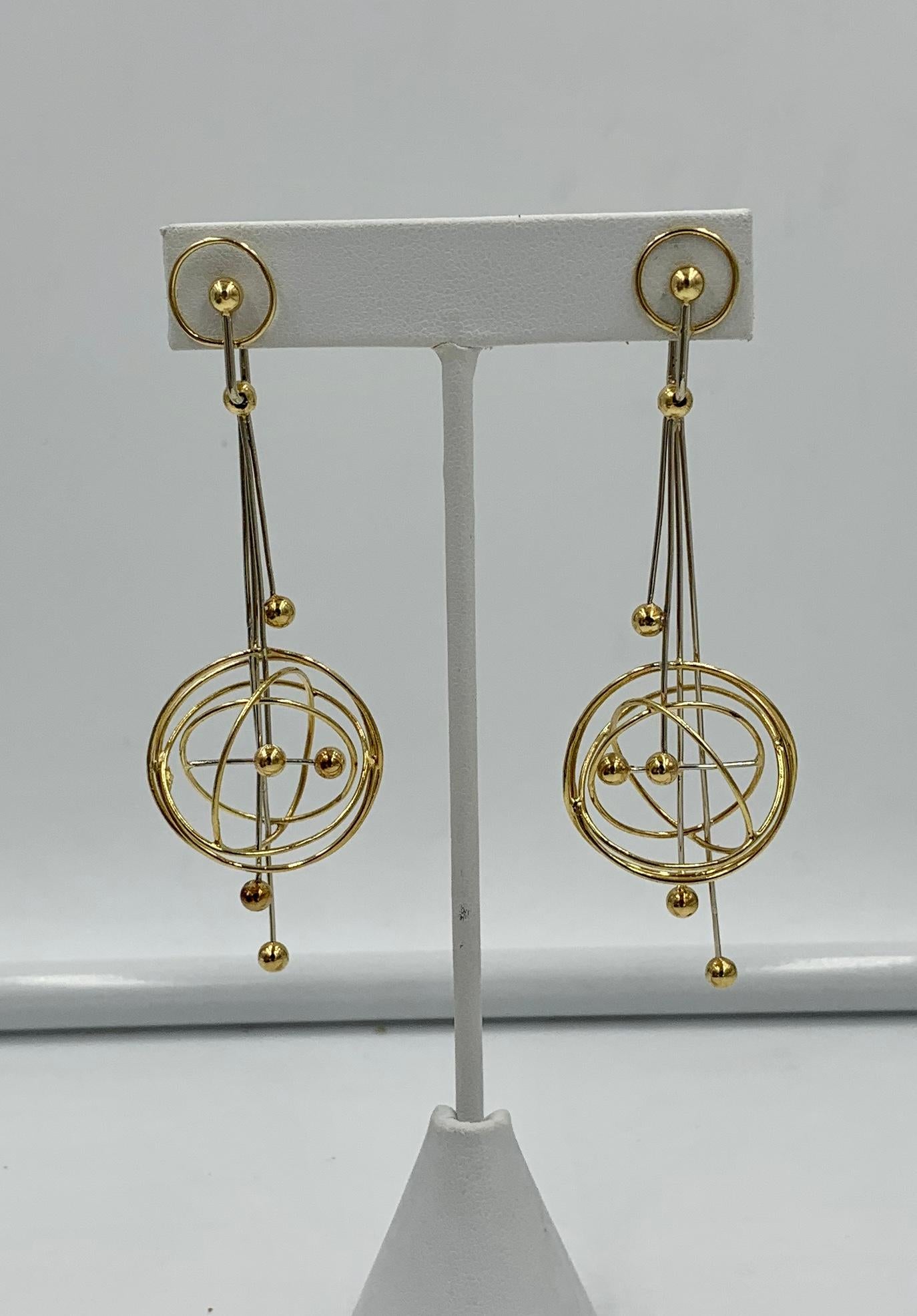 A spectacular pair of 3 3/4 inch long modernist bicolor 18 karat gold drop dangle earrings.  The Retro Sputnik motif is done with wires and spheres in 18 Karat Yellow and White Gold.   The long portion is articulated from the top so the pendants