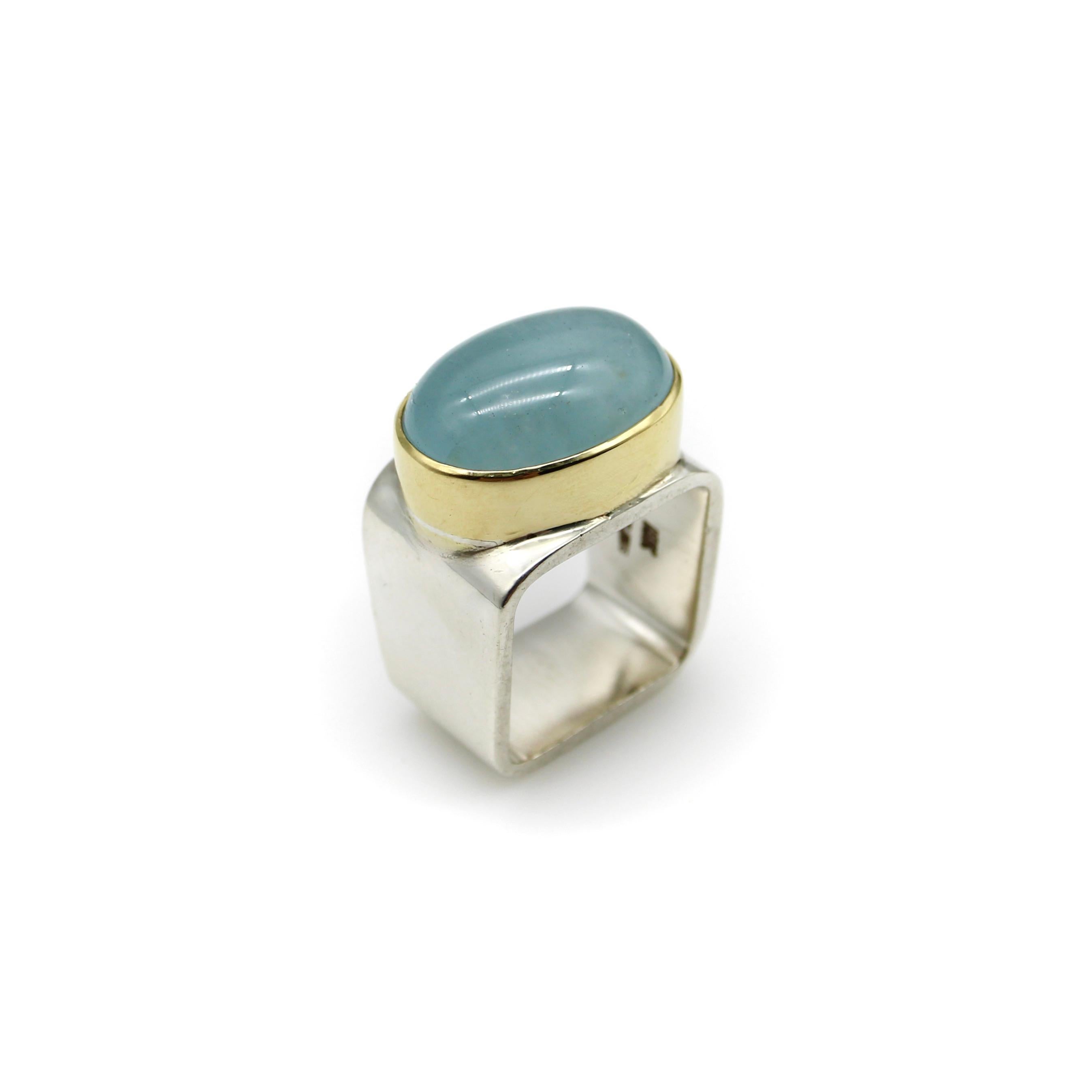 Sleek and sculptural, this 18k gold and sterling silver ring is a contemporary piece with a modern feel. Designed by Gabriel Ofiesh, the ring features an oval aquamarine cabochon in an 18k gold bezel, set into a square sterling silver band. The