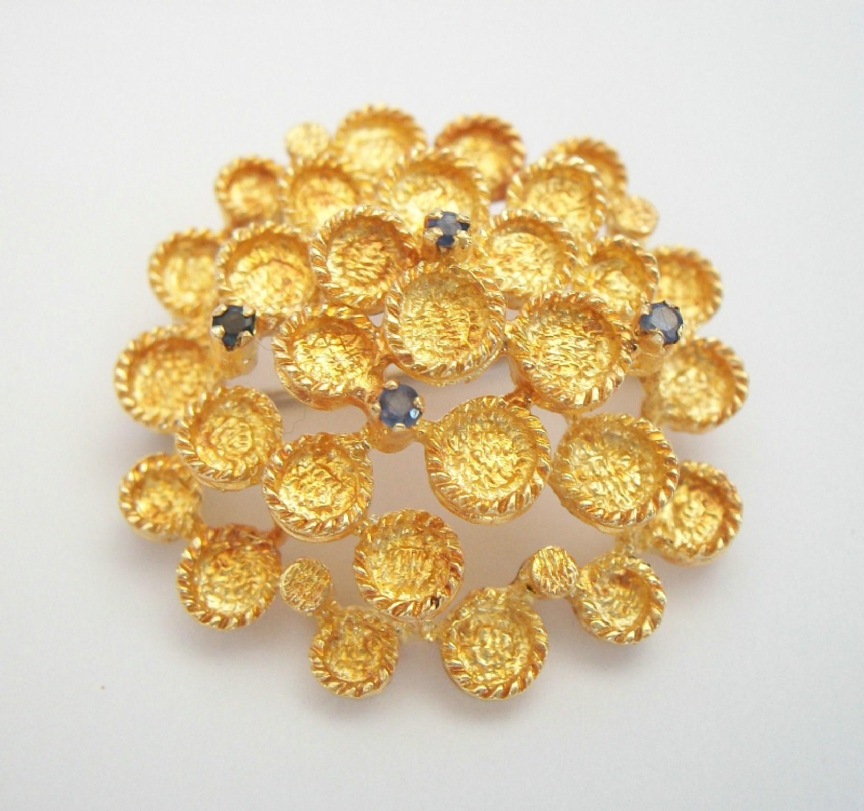 Modernist 18K (.750) yellow gold brooch with four sapphires (each gemstone round faceted - claw set - approx. 1 mm. diameter - approx. 0.07 carat weight total) - hand made featuring fine and elaborate textured finish - original safety catch and pin