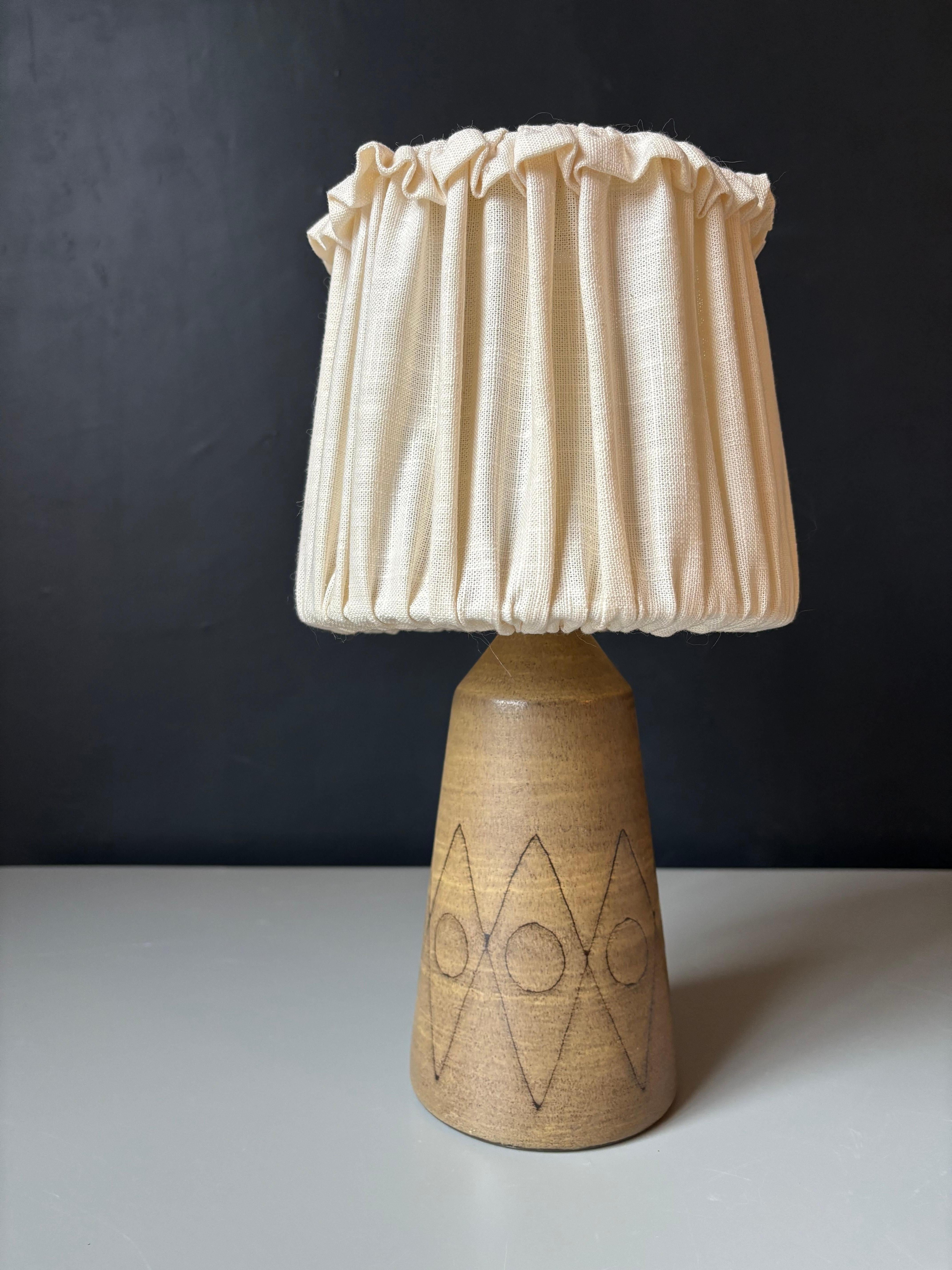 Lampada da tavolo in gres svedese della metà del secolo scorso del designer dell'illuminazione Nils H. Ledung di Jönköping, in Svezia. Decoro grafico intagliato a mano su smalto opaco marrone chiaro. Label all'interno. Cablato per l'uso in Europa e
