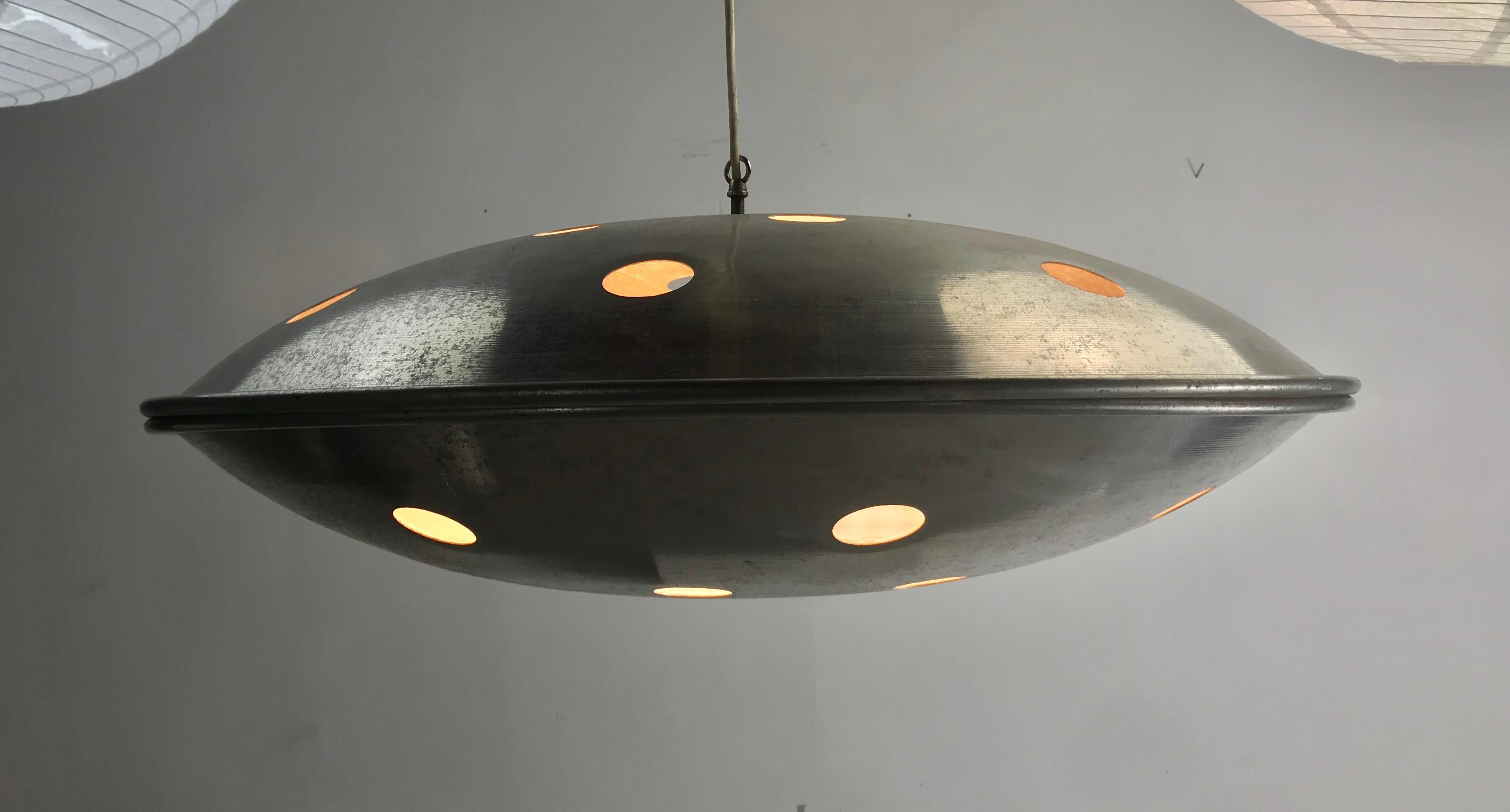 Modernist 1960s Space Age U F O flying saucer hanging pendant light fixture consisting of two spun aluminum concave disks, Space Age pop modern design while remaining elegant, Hanging sculpture, art, holes through the top disk create light beams,