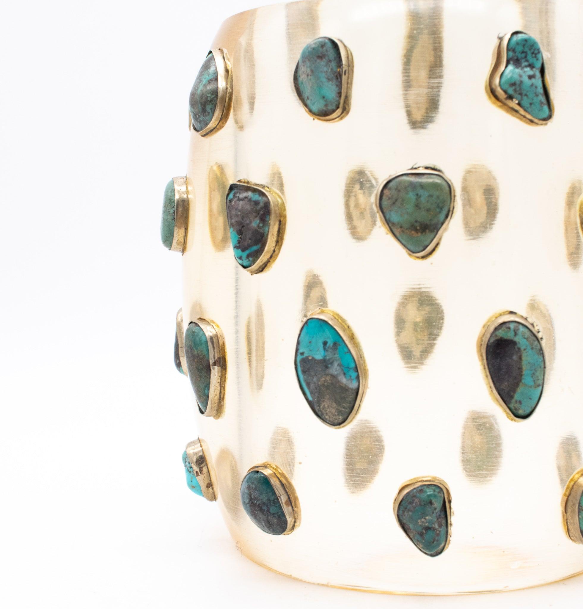 Modernist cuff in Lucite with blue turquoises.

This is a fabulous statement cuff-bracelet, created in America during the modernist period, back in the 1970.The cuff has been crafted in clear Lucite and embellished with bezel settings, which are