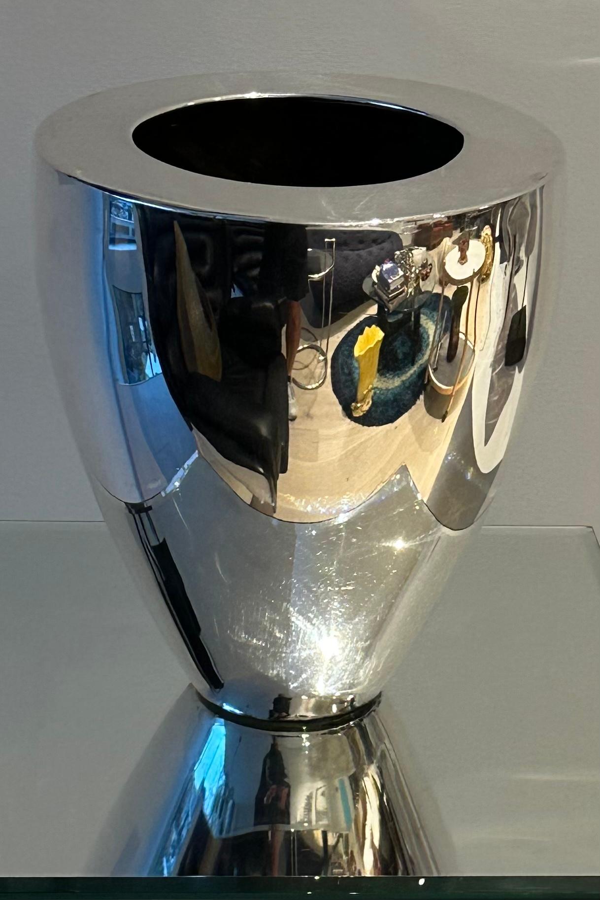 A simple Modernist polished silver-plated vase with a simple yet elegant design. The vase is in a used vintage condition with a small dent on the outer edge of the rim and the base shows some age related wear.  There are some small scratches on its