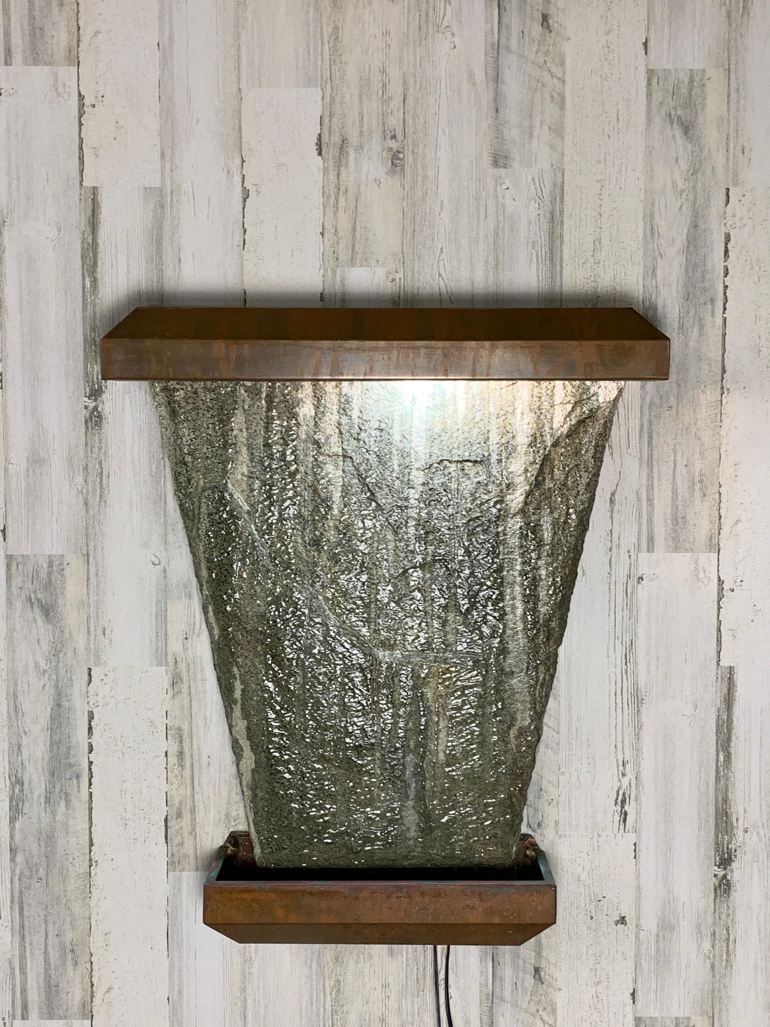 Trapezoid shaped granite wall mounted with copper lighted shroud on top and copper catch basin at the bottom. Nice patina on the copper. shipped in pieces assembly required.