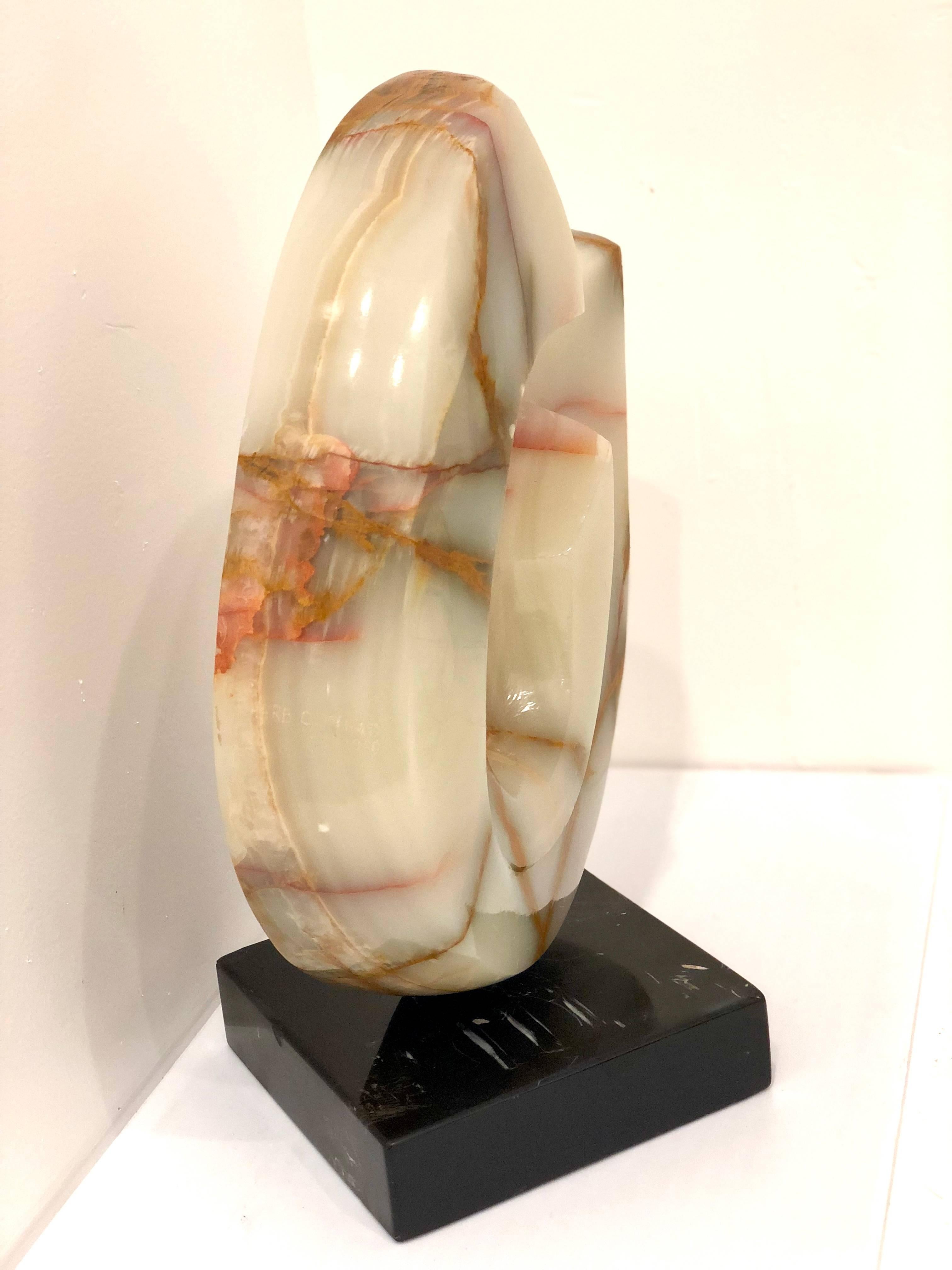 An abstract modernist sculpture carved in onyx, standing atop a base made out of solid black marble. In good vintage condition, with some flea bites on the edge of the back side.