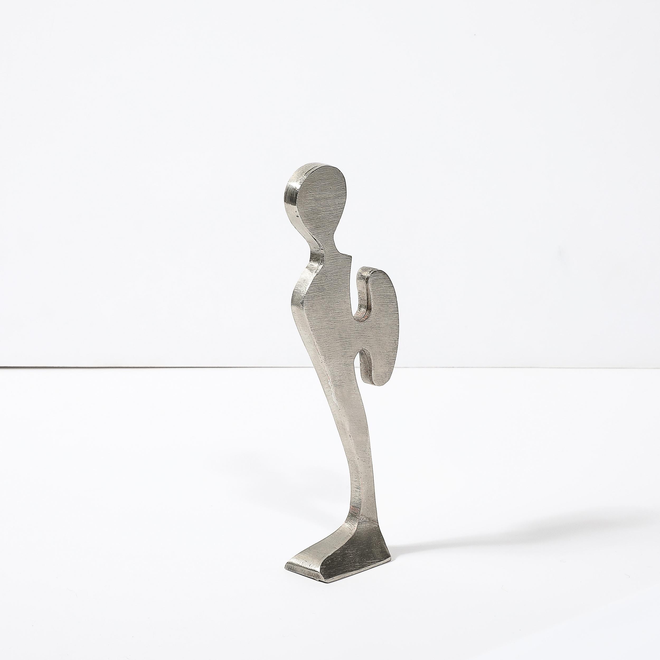 Questa affascinante scultura figurativa astratta modernista in peltro spazzolato di Willi Gutmann proviene dalla Svizzera, CIRCA 1970. Presenta un supporto rettilineo con piedi che si innalza fino a un ritaglio planare di una figura con un pezzo di