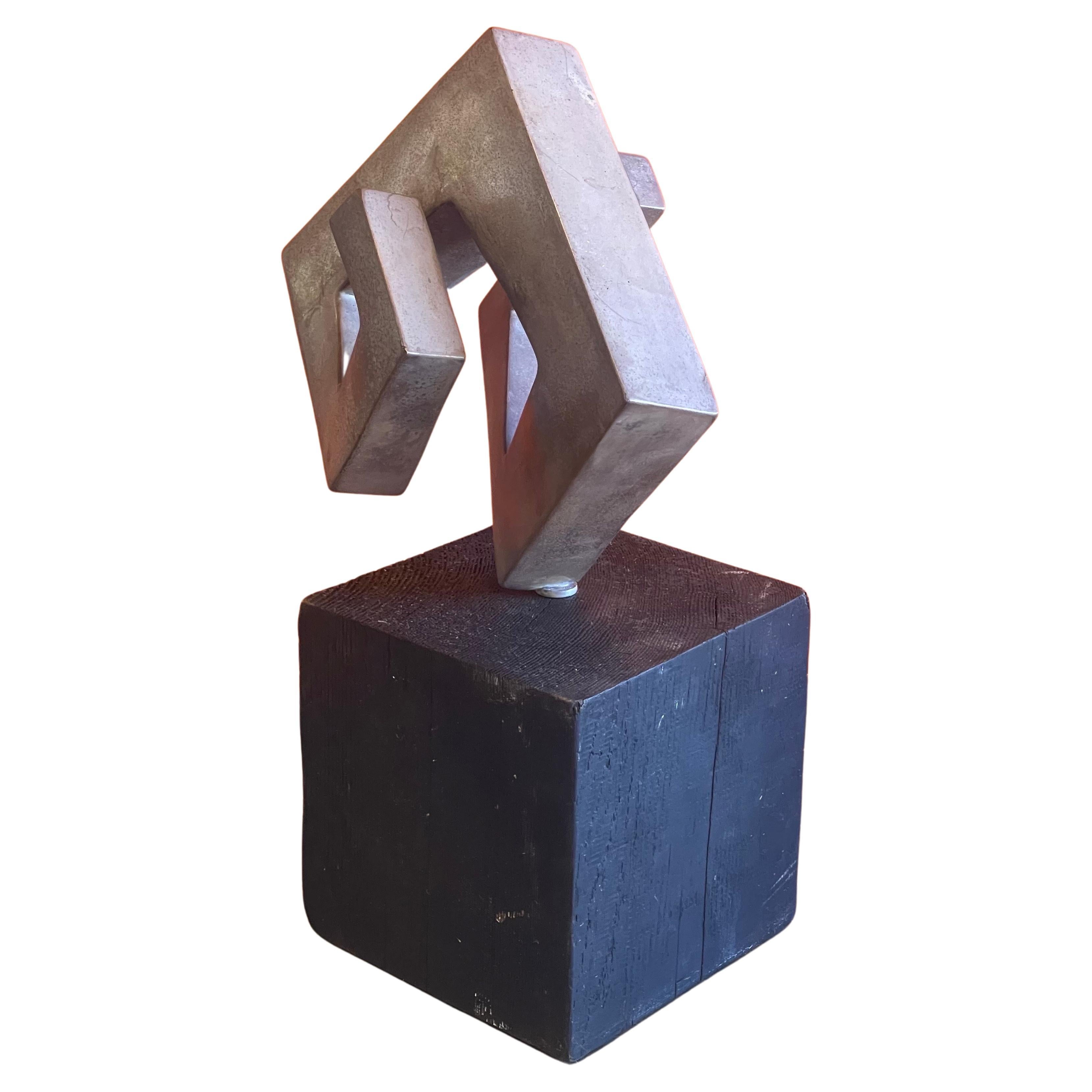 A very cool modernist abstract rotating sculpture on a black wood base, circa 1970s. The sculture appears to be made out of aluminum (not positive - non-magnetic) and can rotate 360 degrees on the base to give the sculpture many different looks; it