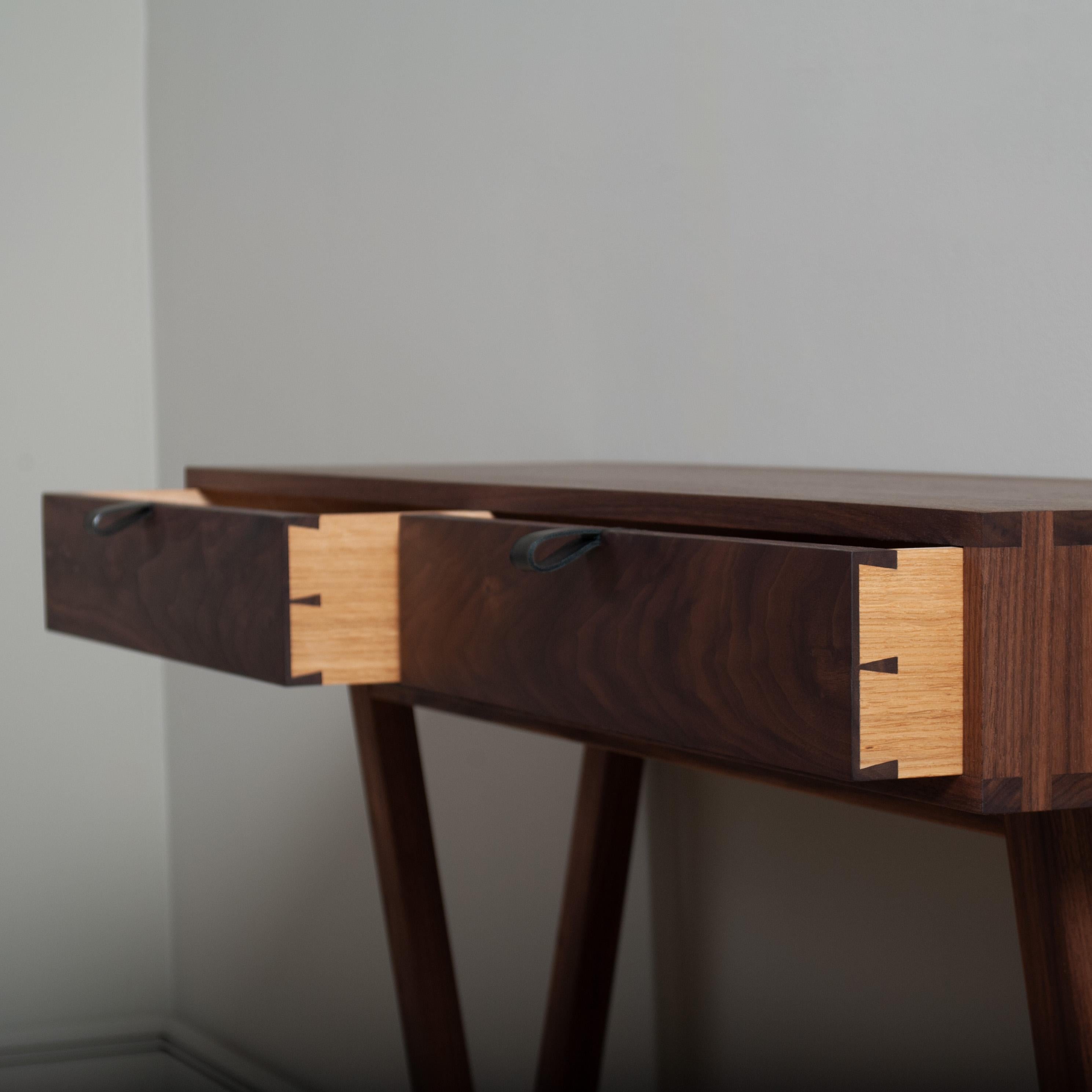 Modernist American black walnut console table designed and produced in England using traditional furniture making techniques. Completely handcrafted from the finest American black walnut. Hand dovetailed joints to the main console drawer box and all