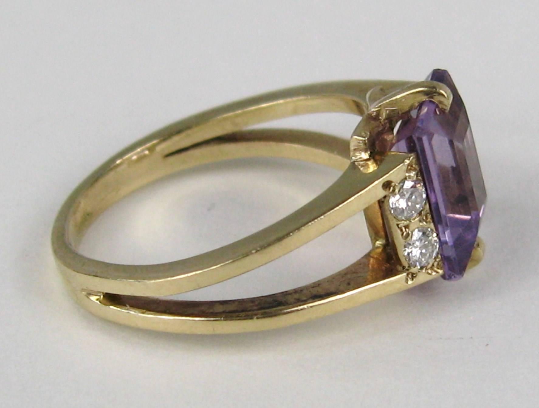 Sleek Modern Amethyst and Diamond Ring. Prong set Amethyst Emerald-cut stone flanked by 2 Diamonds on each side. The ring is a size a 8.5 and can be sized by us or your jeweler. Be sure to check our storefront for more fabulous pieces from this
