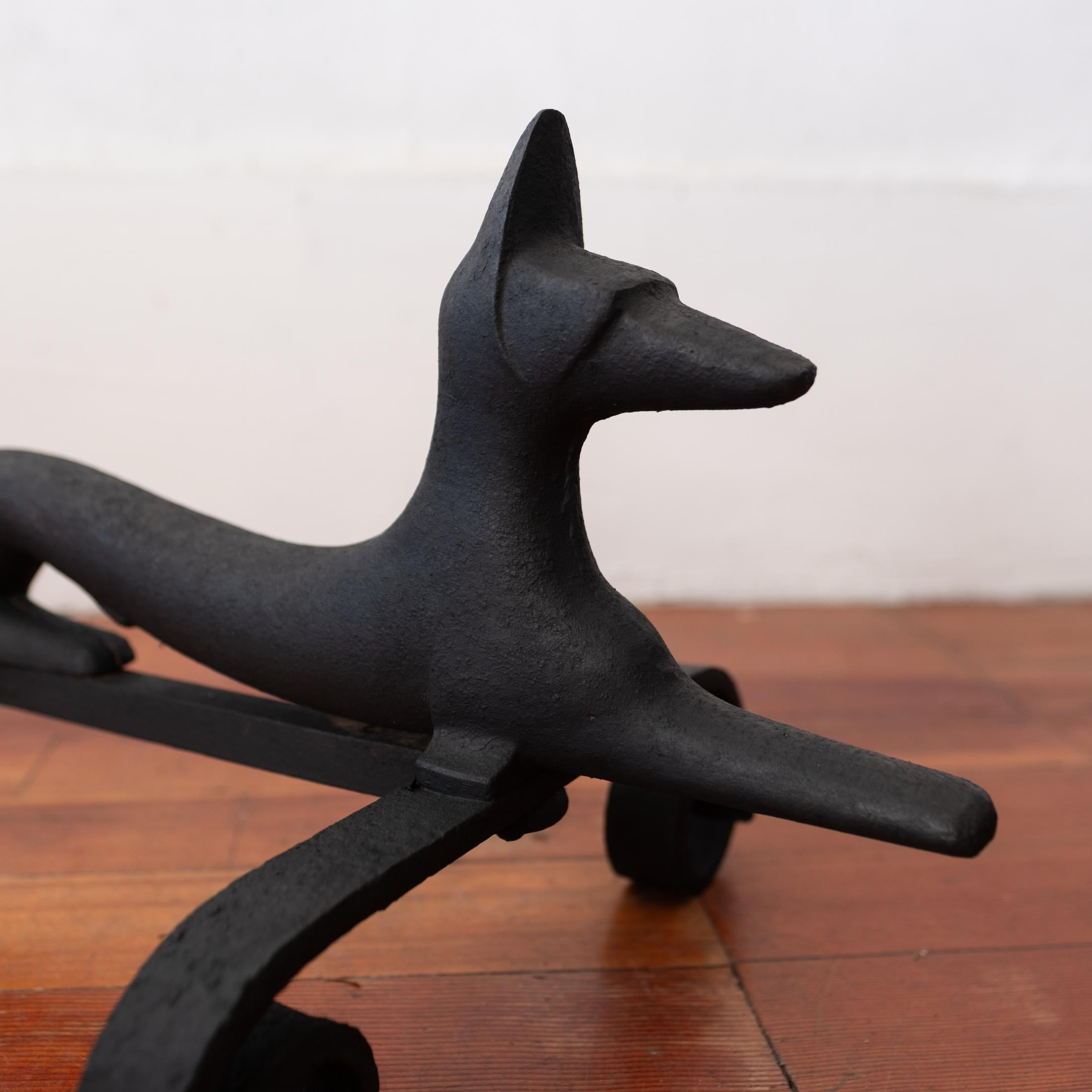 A wonderful pair of modernist stylized dog andirons. Literal fire dogs. Iron. 1940s.