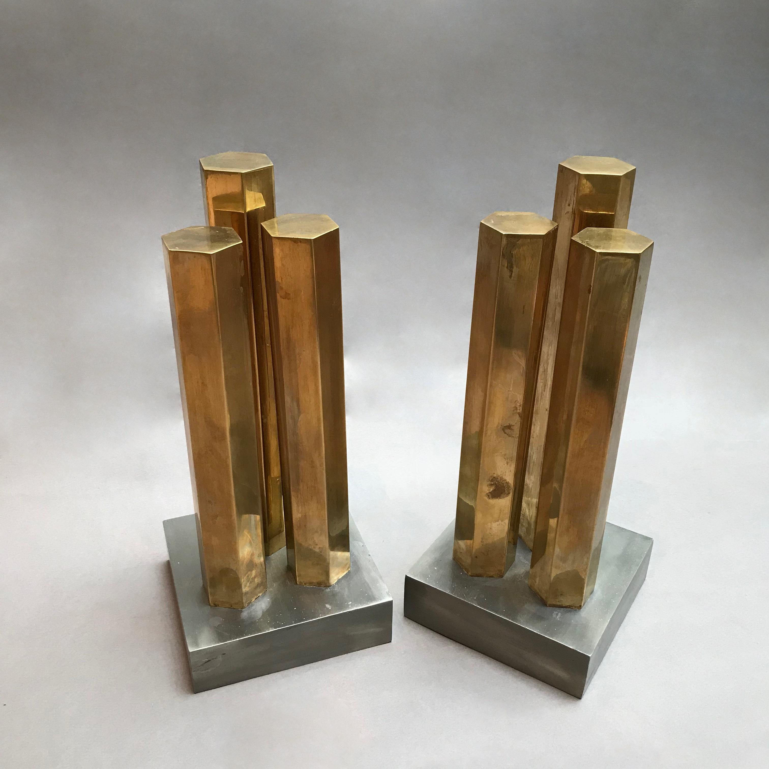 Pair of stunning, modernist, architectural andirons features three graduated, solid brass, hexagonal columns on solid steel bases.