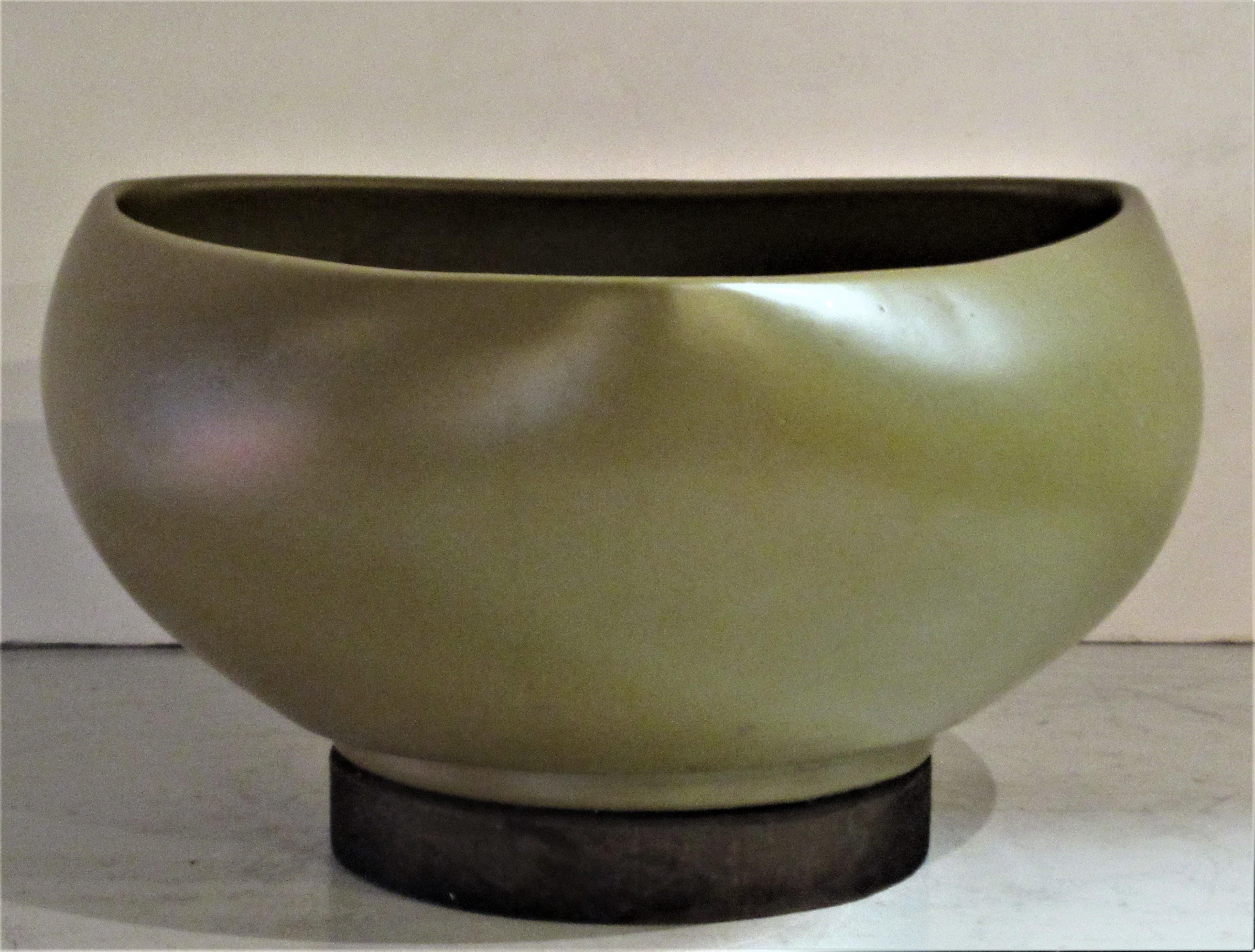 Rich pea color satin glazed architectural pottery planter with a symmetrical rounded spade shape form mounted on circular wood disc base by John Follis for Architectural Pottery, California, circa 1960.