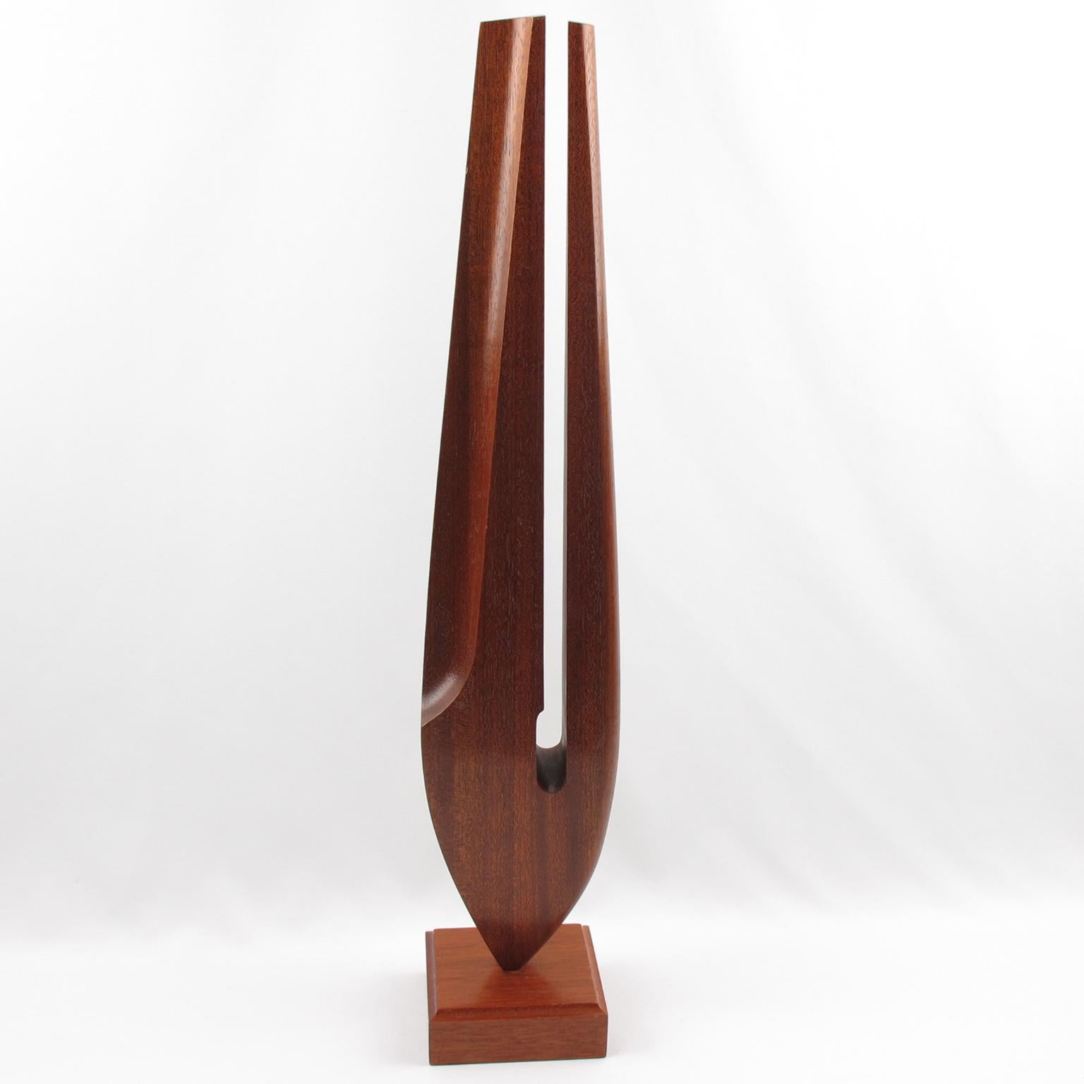 This stunning tropical wood abstract sculpture is architecturally impressive with its stylized tuning fork design. The elongated wooden ornament sits atop a square wood base, featuring geometric lines and golden cut proportions that exude a modern