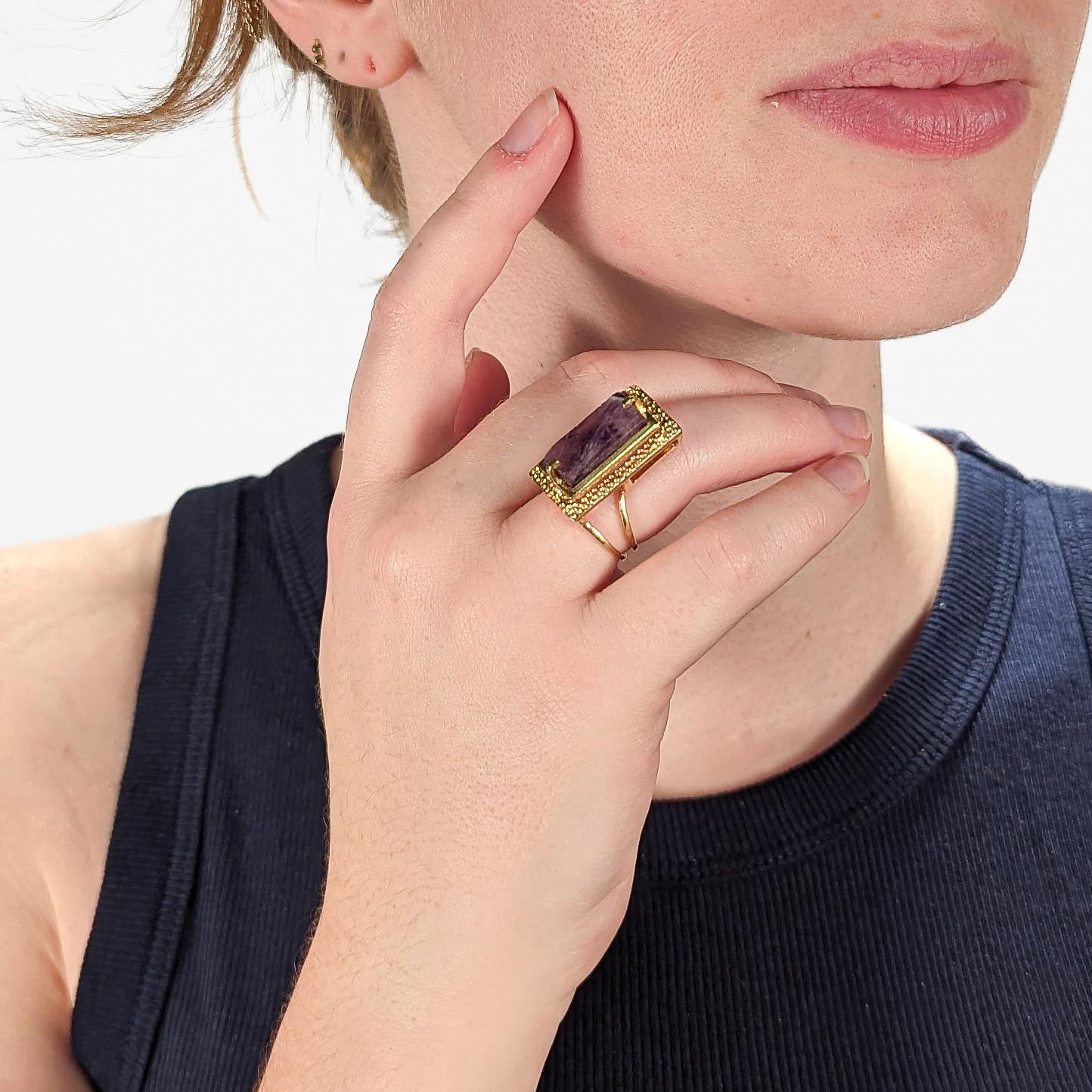 A very fine 18k gold and amethyst modernist cocktail ring.

With a rectangular cut amethyst gemstone prong set above a stippled and hammered platform setting that is supported by an asymmetrical split shank.

Very cool mid-century