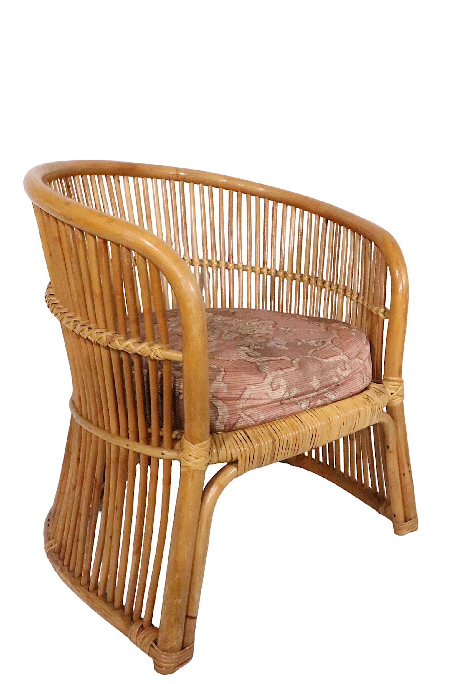 Chic, voguish, architectural arm chair, featuring a wrap around frame of vertical reeds, attached to a bamboo frame. This example comes with the seat and back rest cushion, both show wear, but are included. The chair was executed in the style of