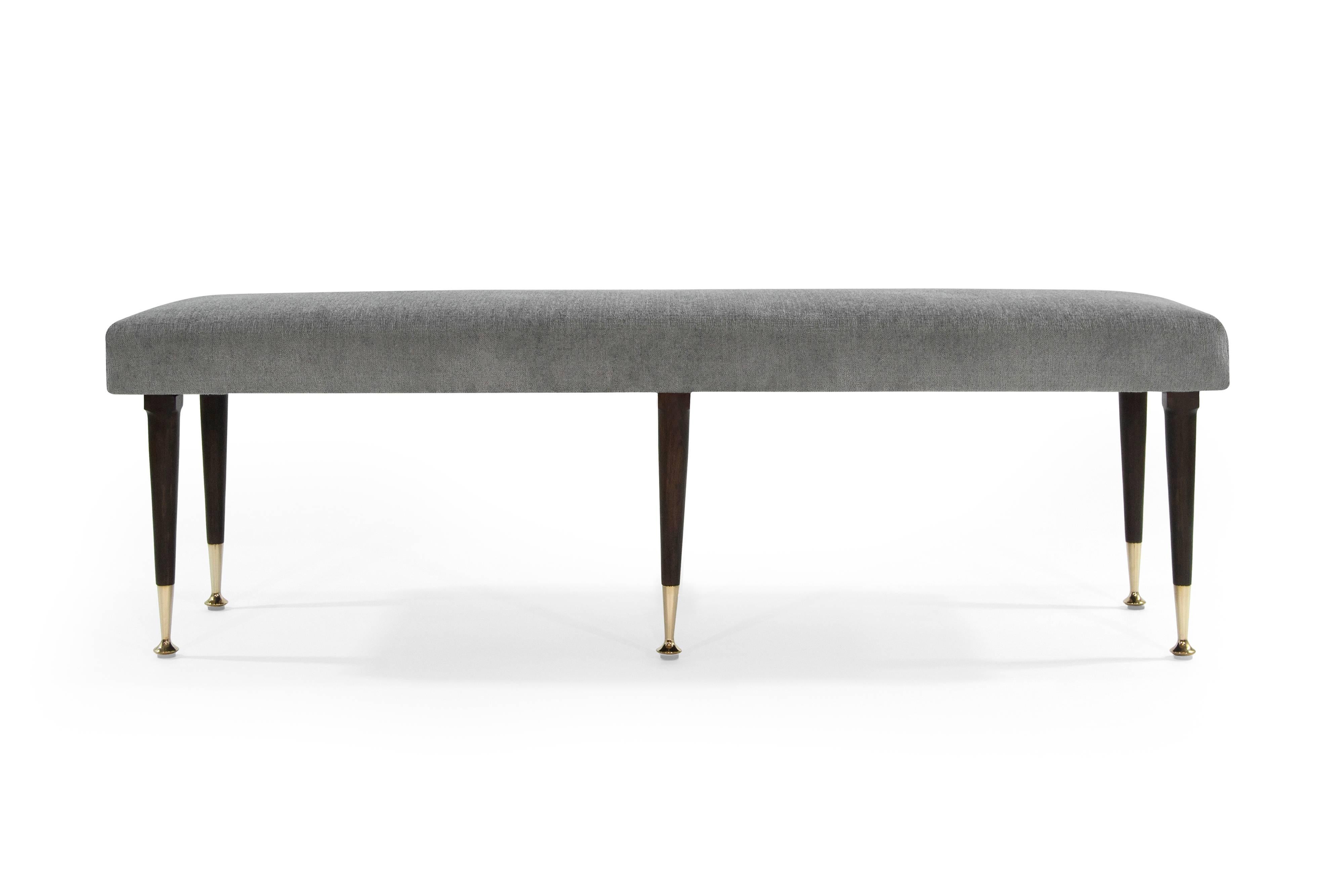 Fully restored 1950s bench. Boasts clean lines; newly upholstered in grey chenille. Fully restored walnut legs ending in stylish brass sabots. In style of Gio Ponti.
