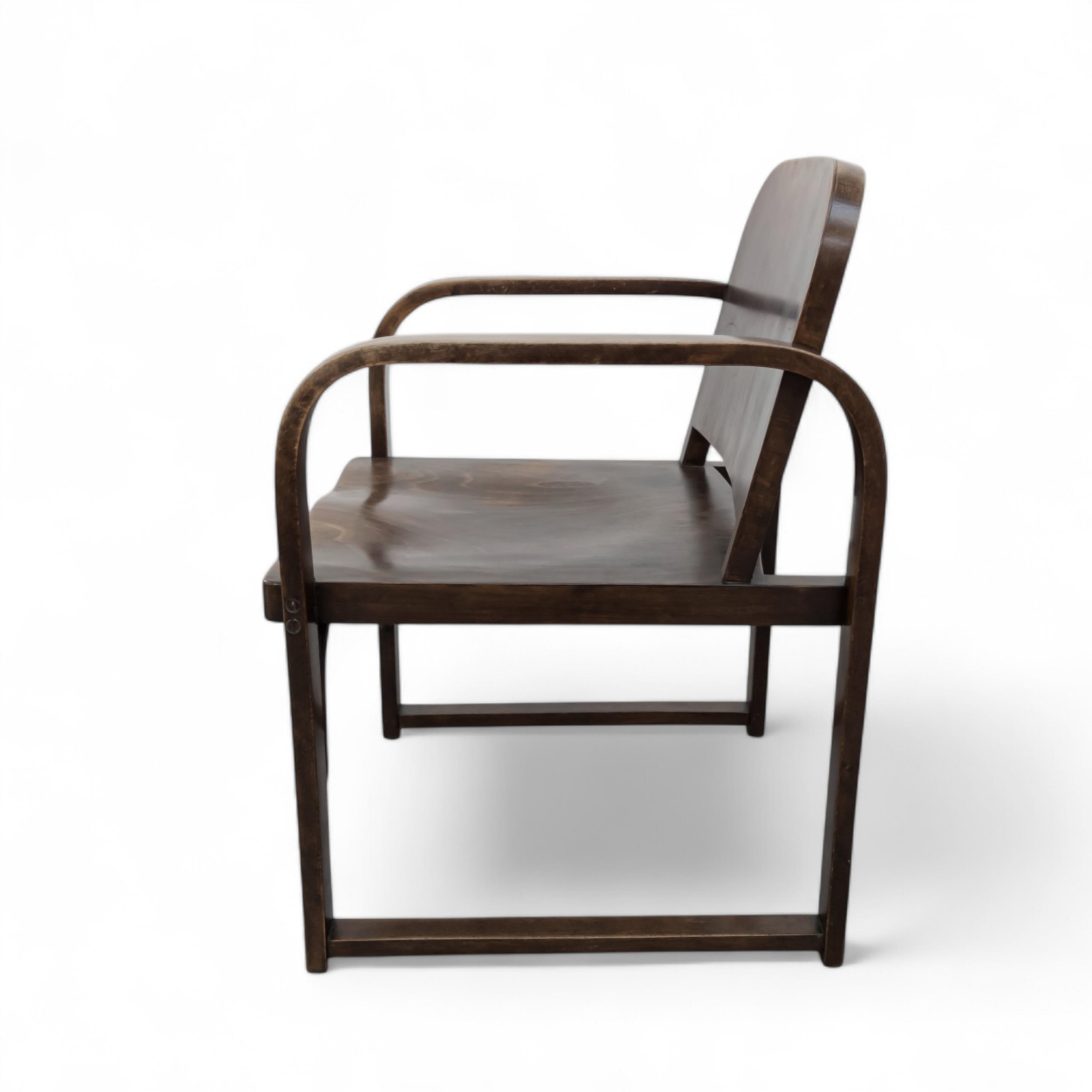 Este elegante sillón modernista de madera curvada fue concebido originalmente por Thonet en la década de 1930 para la empresa zapatera Baťa de Zlín, en la entonces Checoslovaquia. Diseñado como modelo A 745 F, encarna la estética limpia y funcional