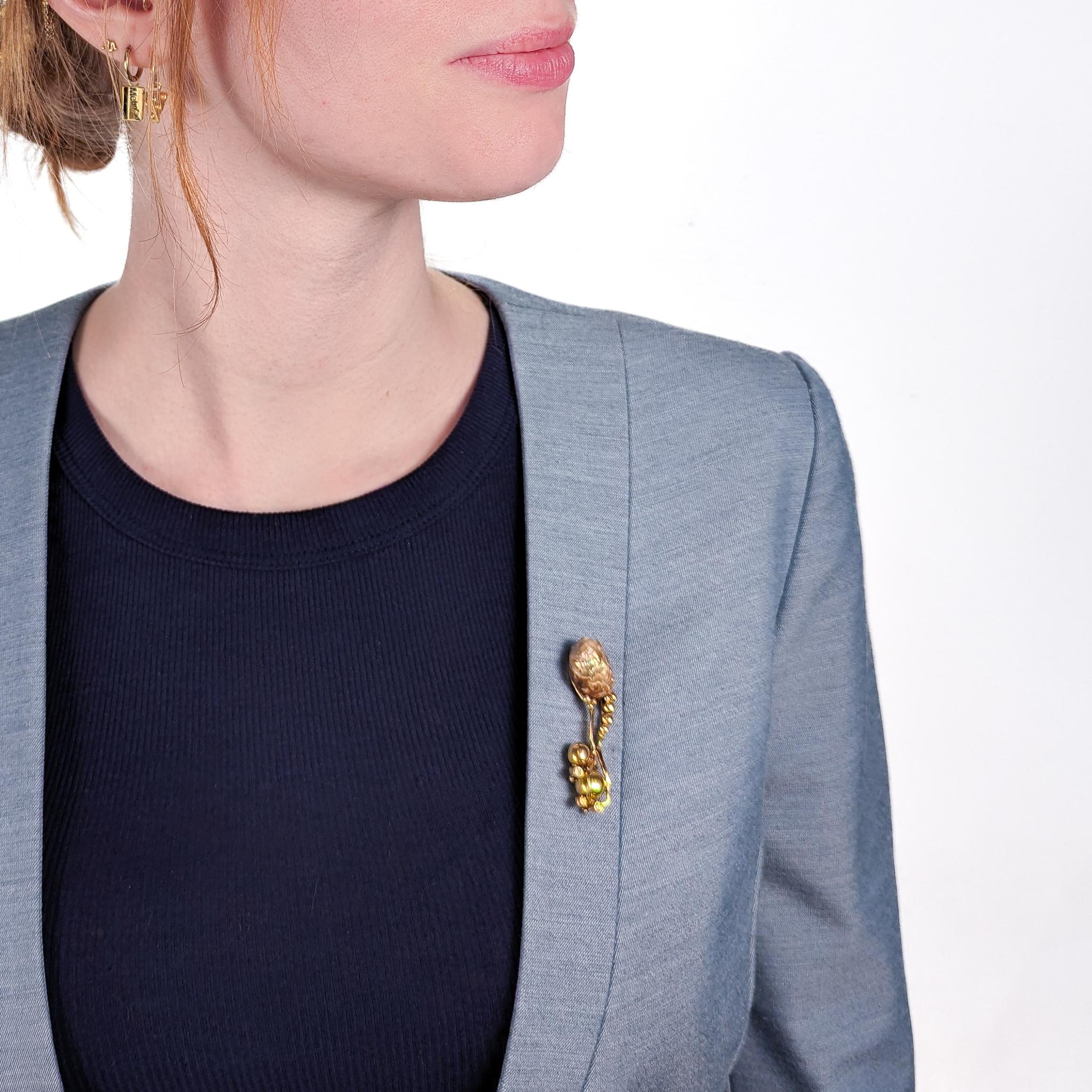 Une broche biomorphique moderniste étonnante.

Façonnée presque comme une créature marine, la grande perle tire derrière elle des vrilles avec des bulles d'or et de diamants. 

En or jaune 14K avec une perle baroque violet-vert et des diamants