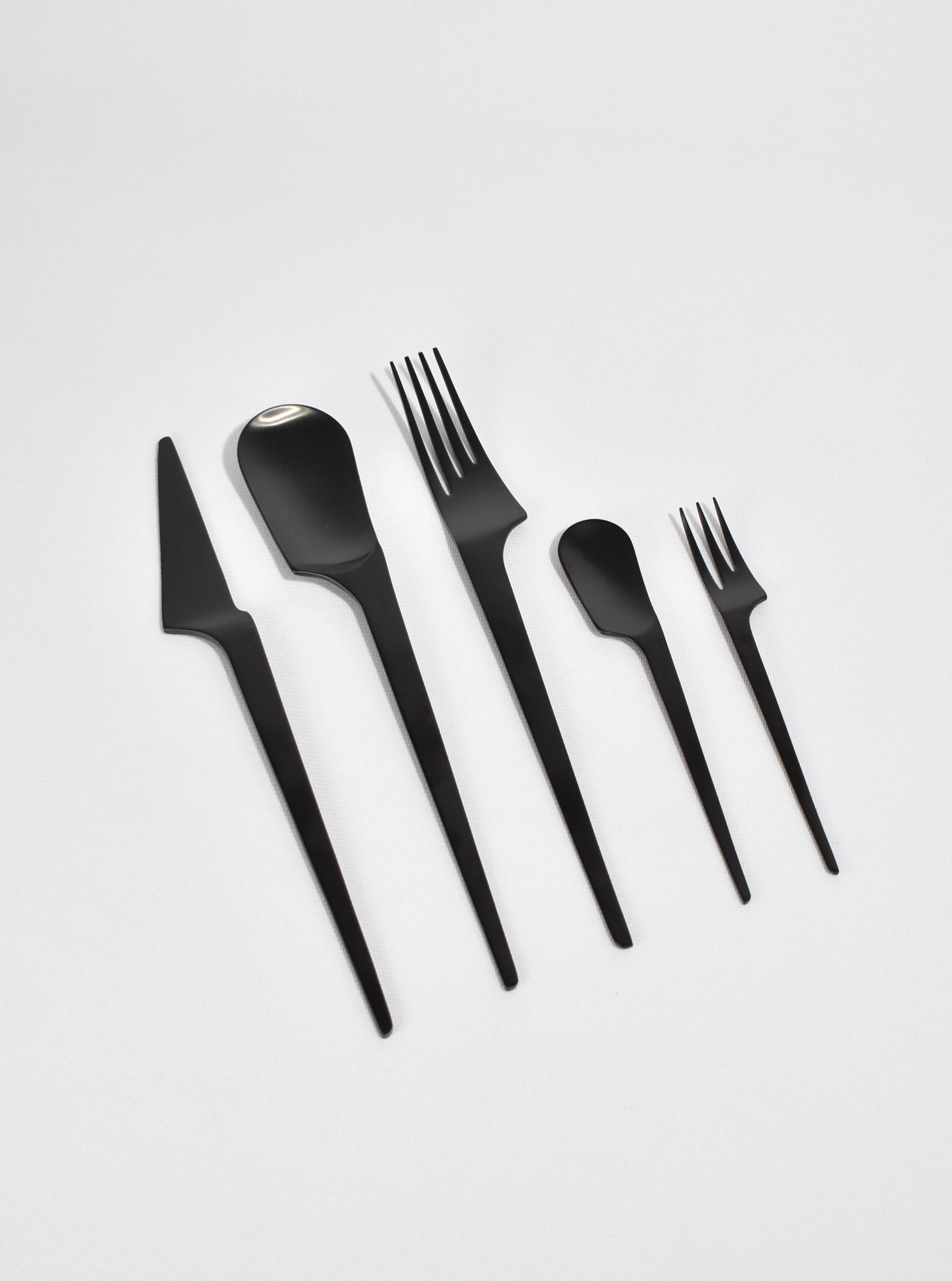 Flatware set of five pieces with a modernist sculptural shape in black coated brushed stainless steel. By Herdmar, made in Portugal. 

Purchase includes one set of five pieces (one knife, two forks, two spoons). Ten sets available.

Care: