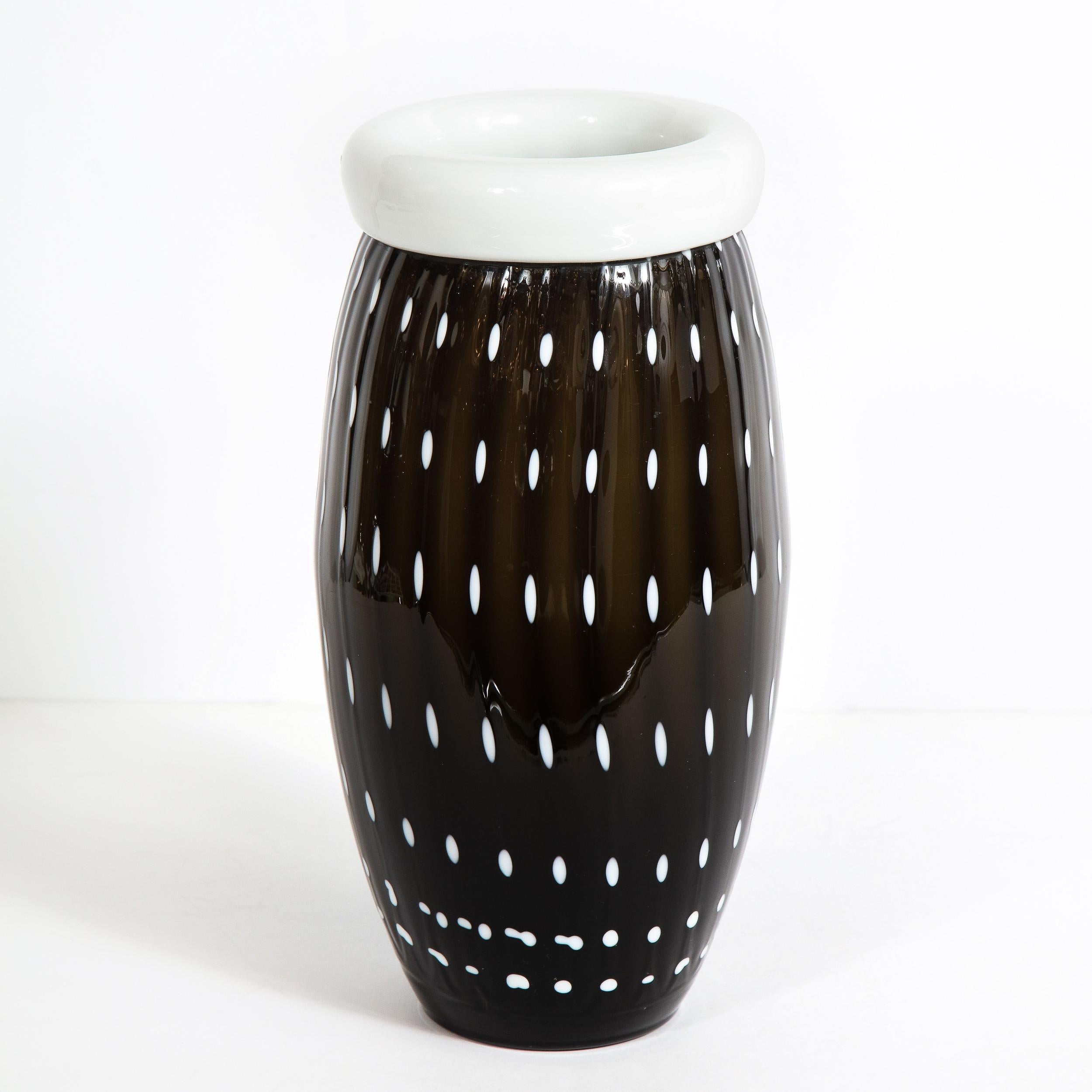 This elegant modernist black and white vase was realized in Murano, Italy- the island off the coast of Venice renowned for centuries for its superlative glass production. It features a cylindrical body that tapers to each end with a white banded