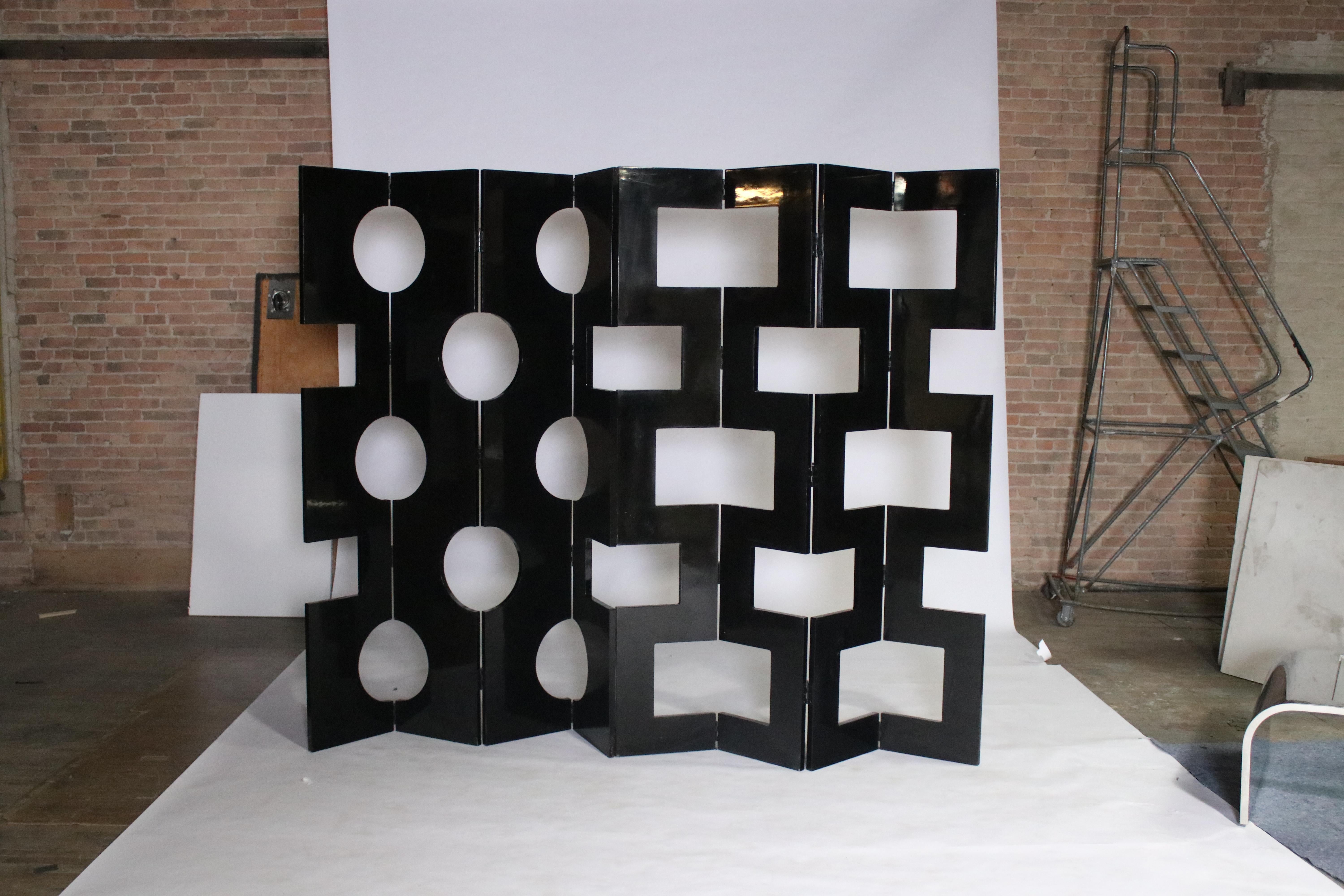 2 Four-panel modernist black lacquered room dividers sourced from vintage Saks 5th Avenue prop displays. Each panel is lacquered on both sides one with round circle holes and the other with square holes. They can be displayed together by hinges or