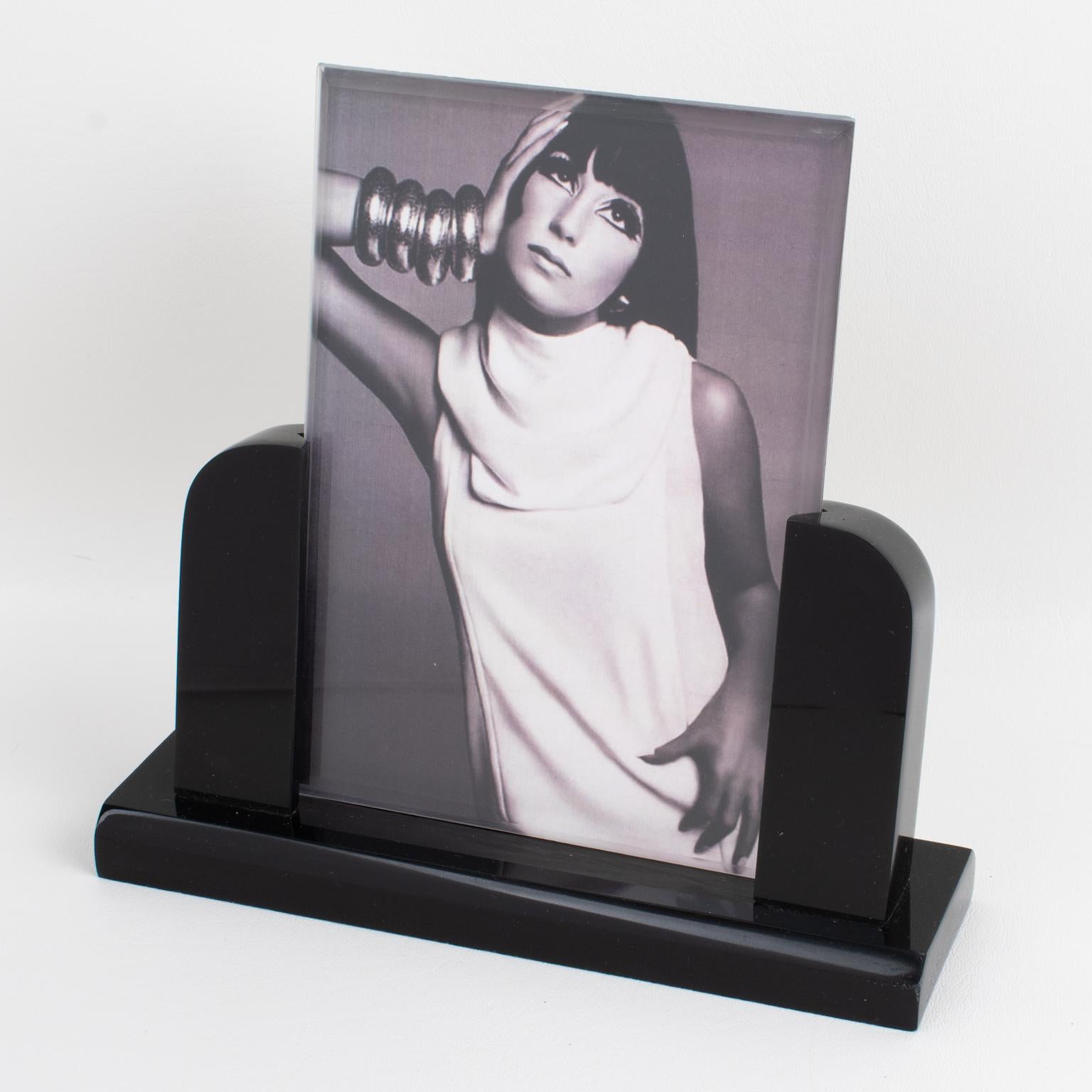 Dieser atemberaubende modernistische Bilderrahmen aus Lucite wurde um 1980 in Italien hergestellt. Der Fotorahmen verfügt über einen massiven, tiefschwarzen Lucite-Sockel mit Abschrägung, der von geschnitzten Stangenhaltern gekrönt wird. Zwei