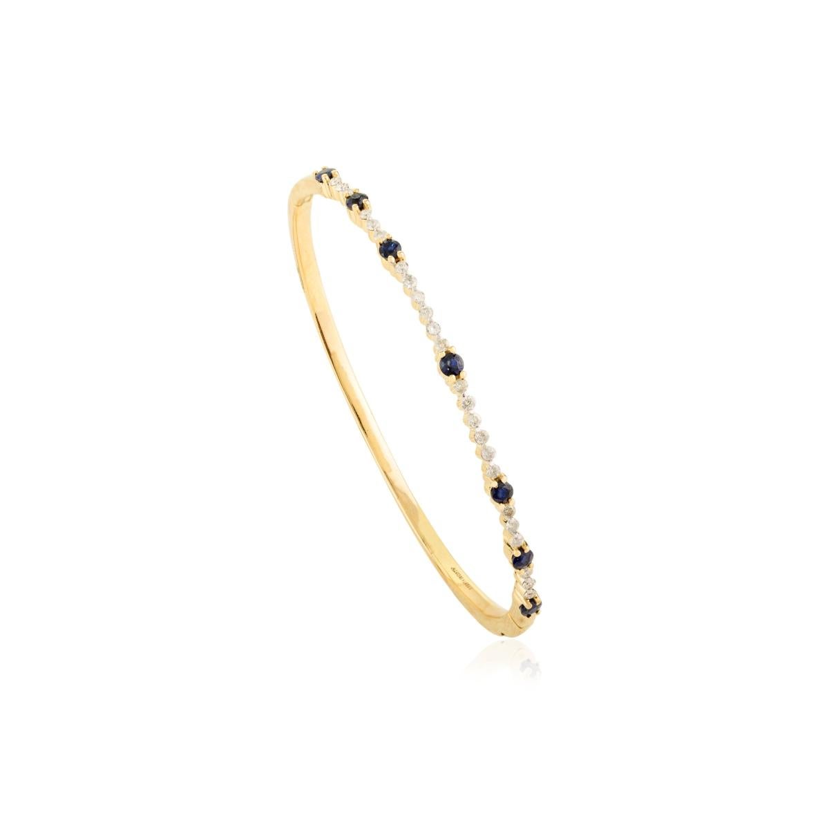 Ce bracelet en or jaune 14 carats est orné d'une alternance de diamants étincelants et de saphirs bleus profonds d'une valeur totale de 0,75 carat. Sa silhouette élégante et ses détails délicats sont parfaits pour être empilés ou portés seuls pour