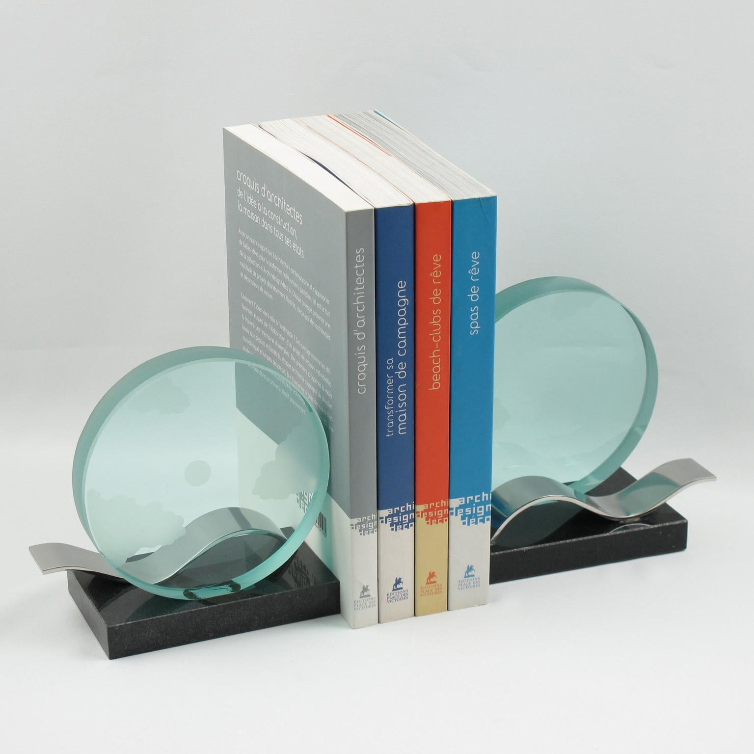 This architecturally designed pair of bookends from the 1980s is a modernist marvel. The large round disk glass slab is etched with clouds and dots, and the base is constructed of black granite with a large chromed metal wave. These decorative