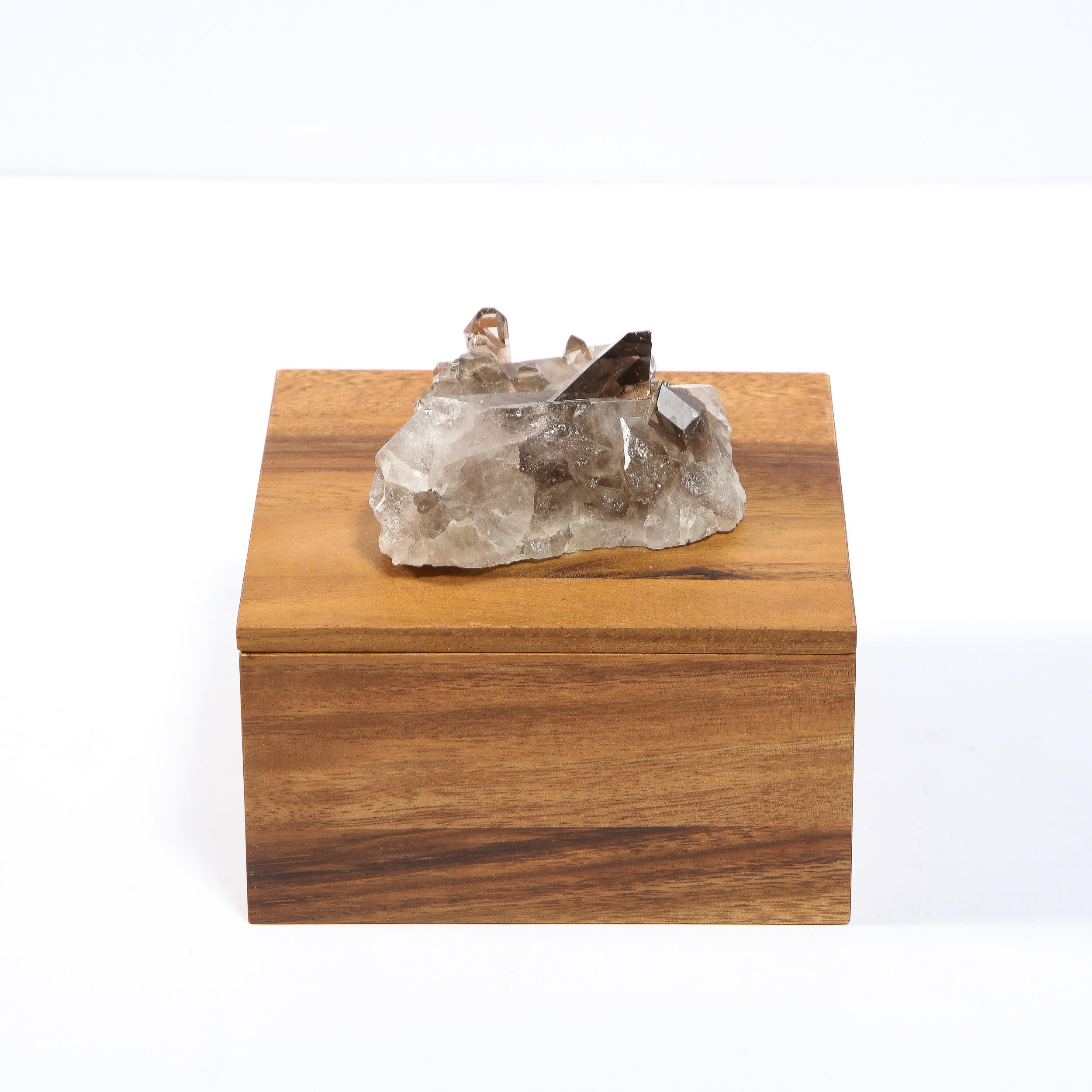 This sophisticated modernist box was realized in the United States during the 21st century. It features a cubic body in bookmatched walnut with an embellishment (that doubles as a handle) in beautiful organic smoky quartz that offers a striking