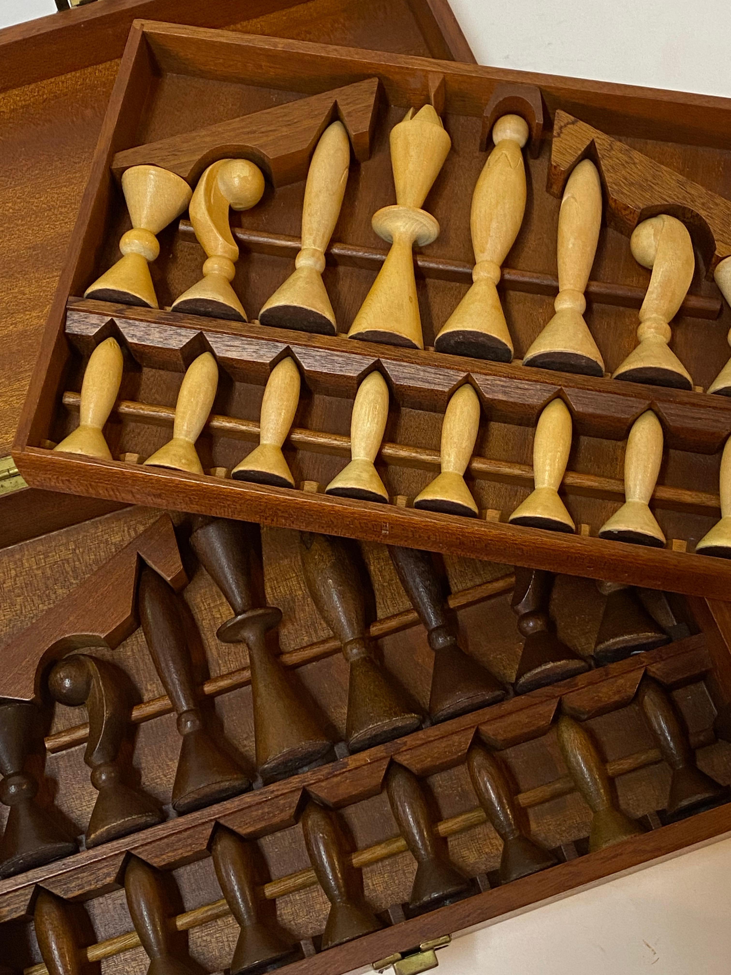 A fine boxed set of carved wood modernist chessmen. The two sets are made of hardwood and sculpturally carved into very stylized forms. One set is in a blonde wood natural finish and the other set is a brown walnut. All pieces are present. Circa